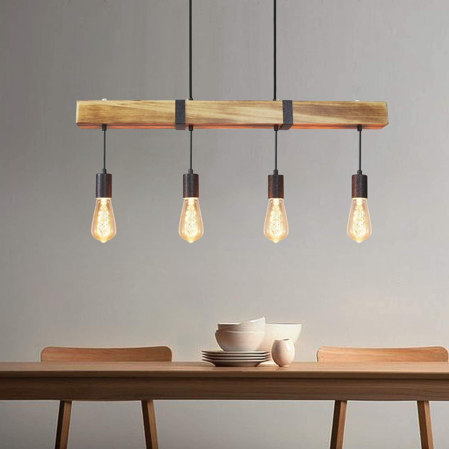 Lampadario a trave in legno con quattro lampadine stile Edison, sopra un tavolo.