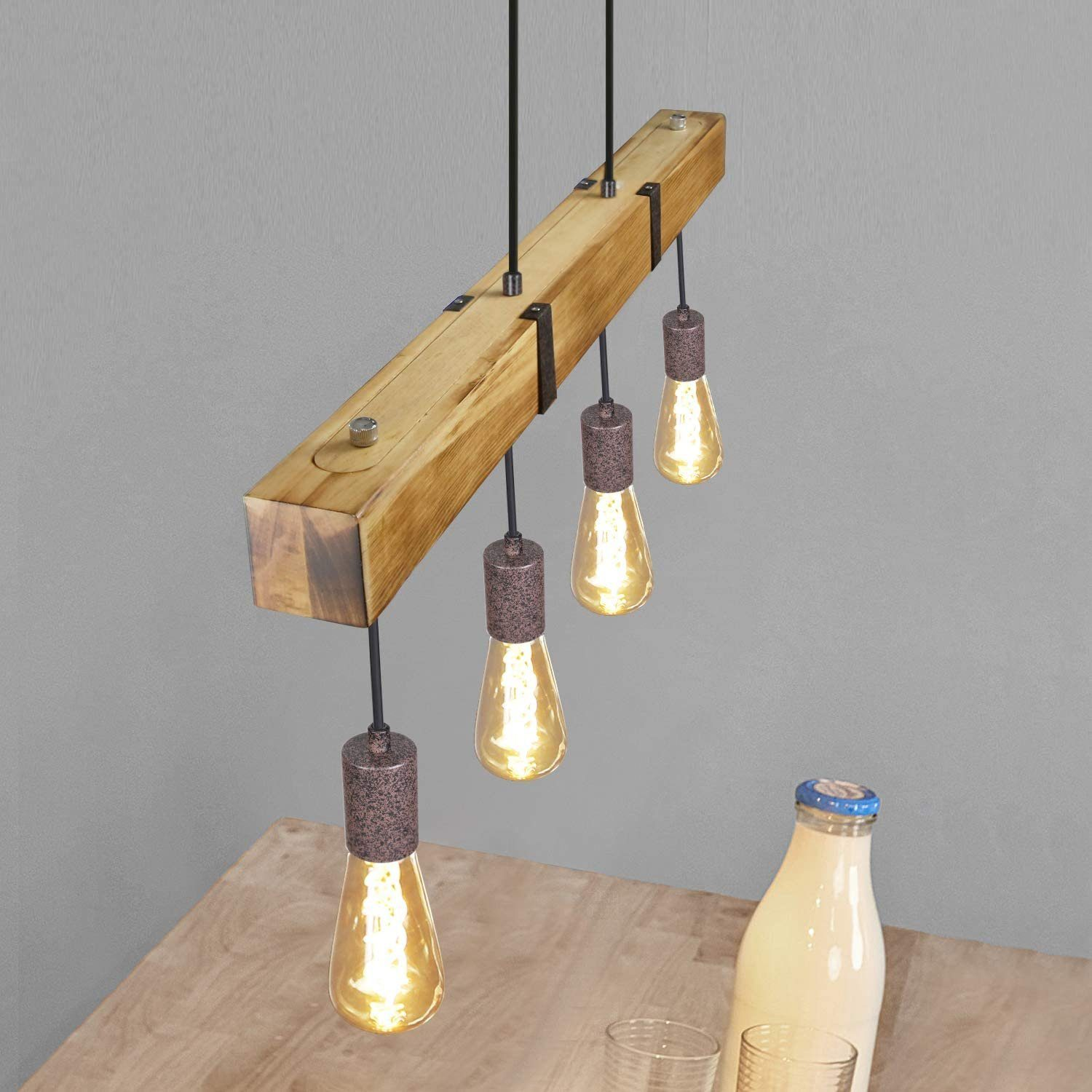 Una trave di legno con quattro lampadine appese. C'è una bottiglia di latte sul tavolo.
