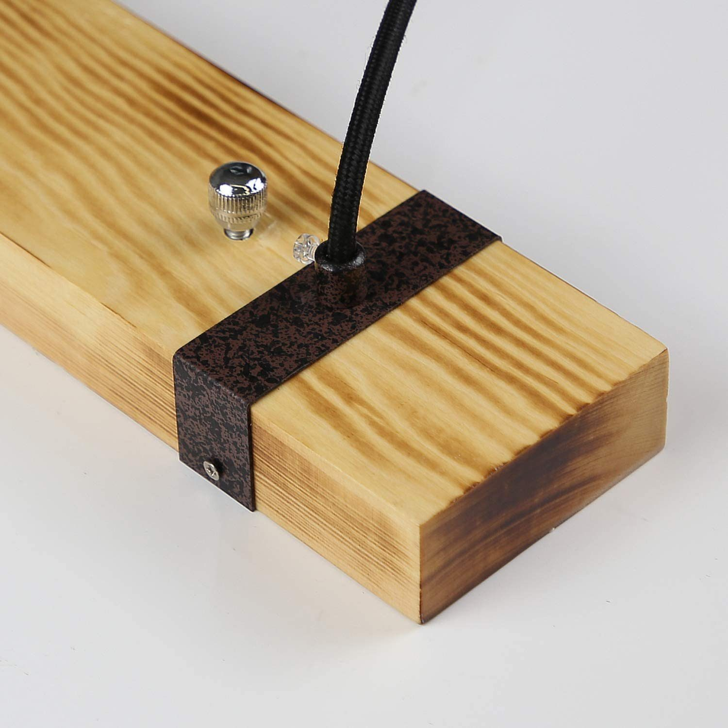 Primo piano di una tavola di legno con una cinghia di metallo. Un cavo è attaccato al legno.