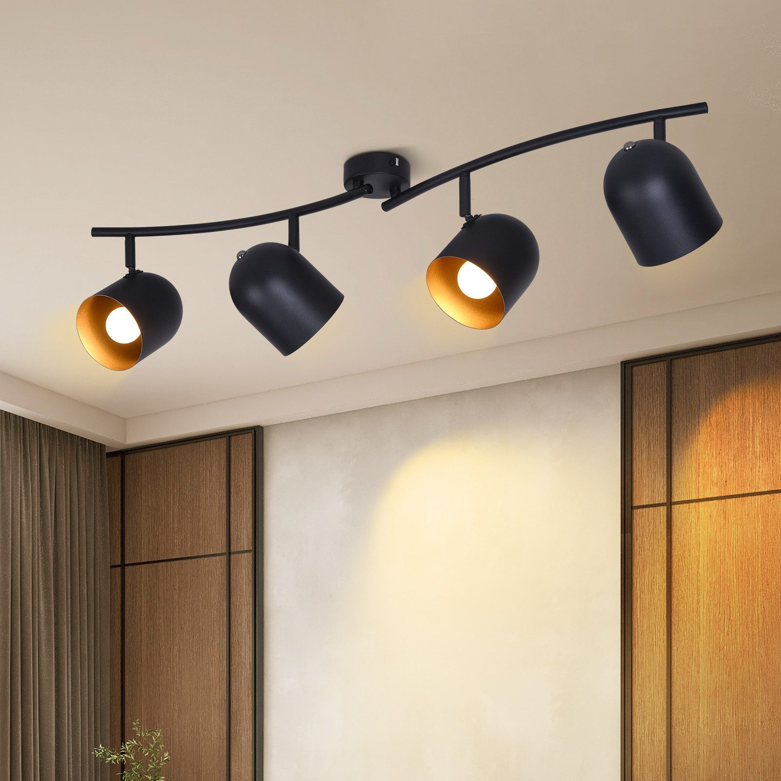 Quattro faretti neri su un binario curvo, montati a soffitto. Le luci hanno riflettori interni dorati.