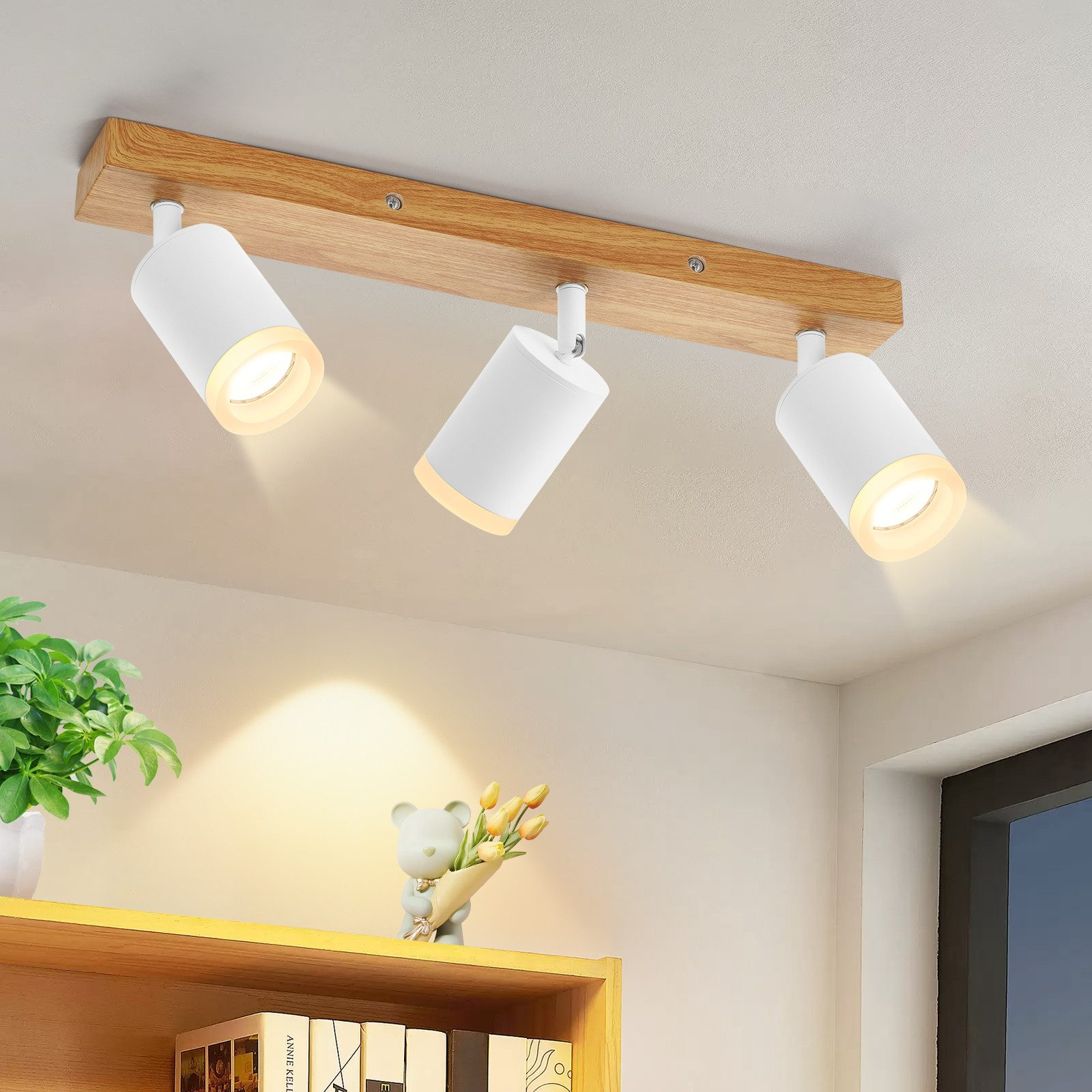 Tre faretti bianchi su una trave di legno. Sono montati sul soffitto.