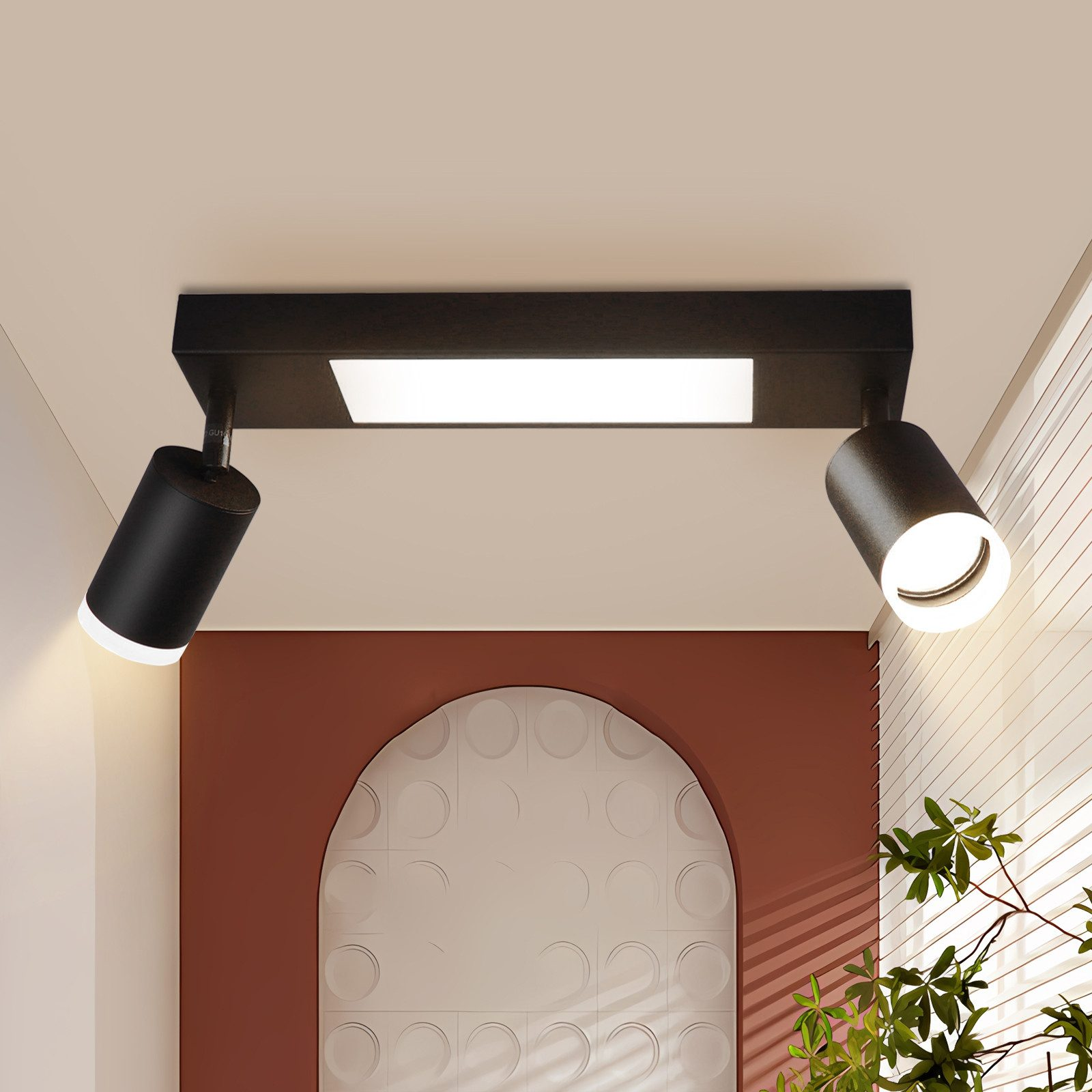 Due faretti neri fissati a una base nera, montati su un soffitto bianco con una parete rossa.