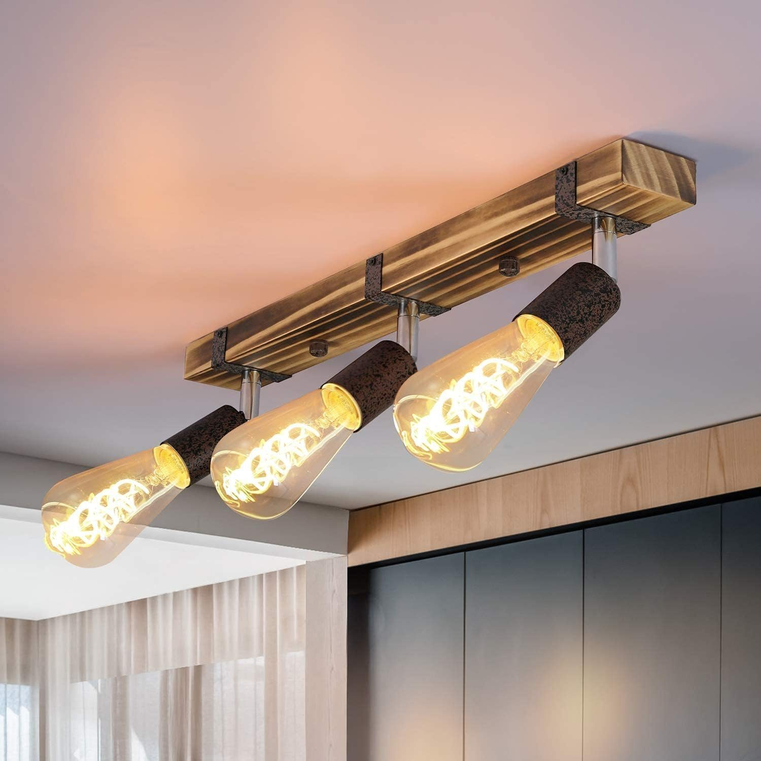 Lampada da soffitto con tre lampadine in stile Edison. L'apparecchio è montato su una trave di legno.