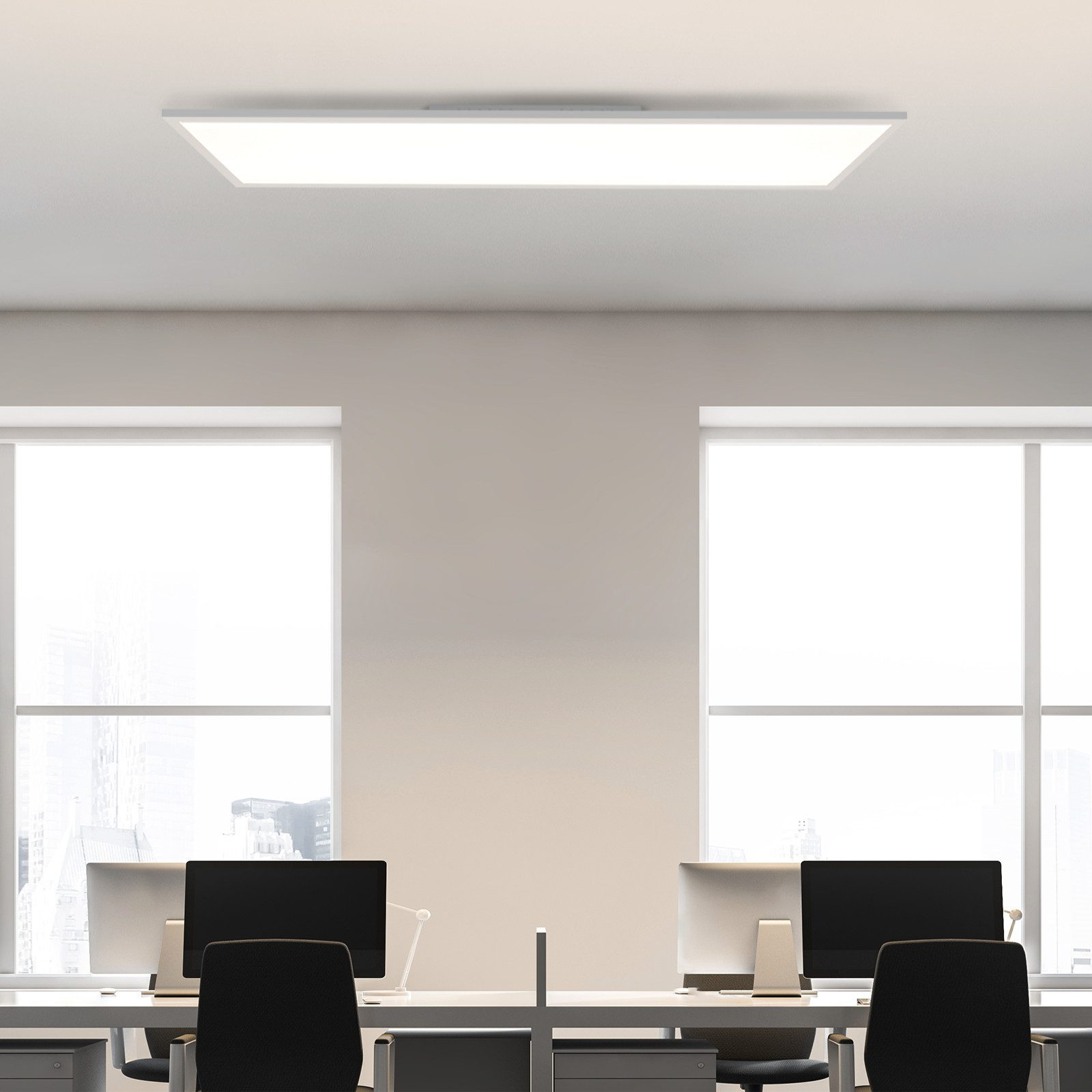 Due scrivanie con computer sotto una luce a soffitto rettangolare. Finestre sullo sfondo.