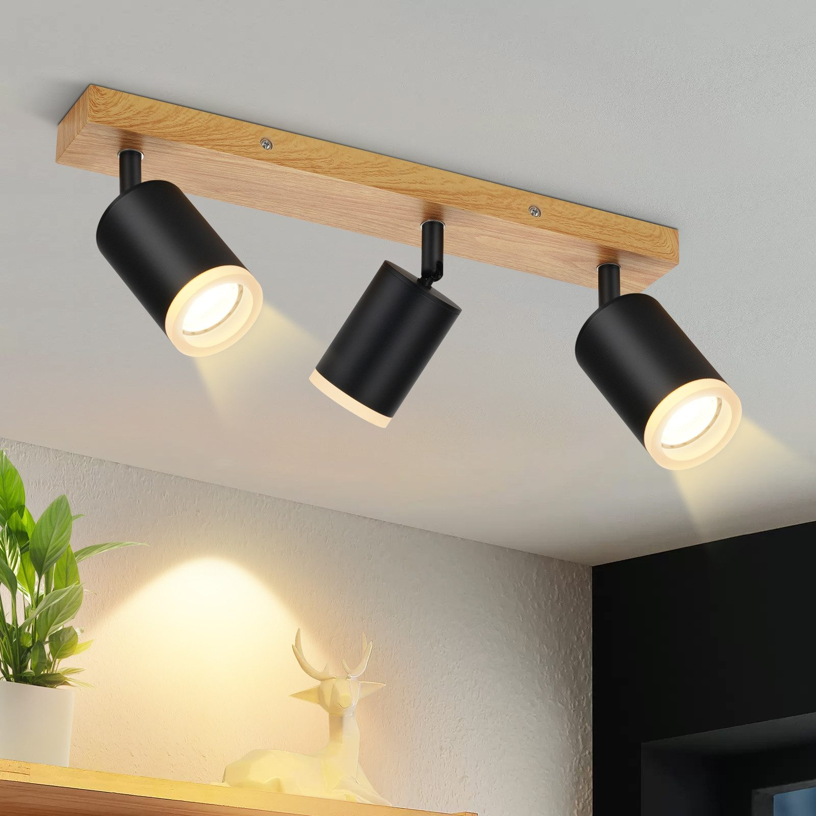 Tre faretti neri su una tavola di legno, montati su un soffitto bianco. Sfondo sfocato.