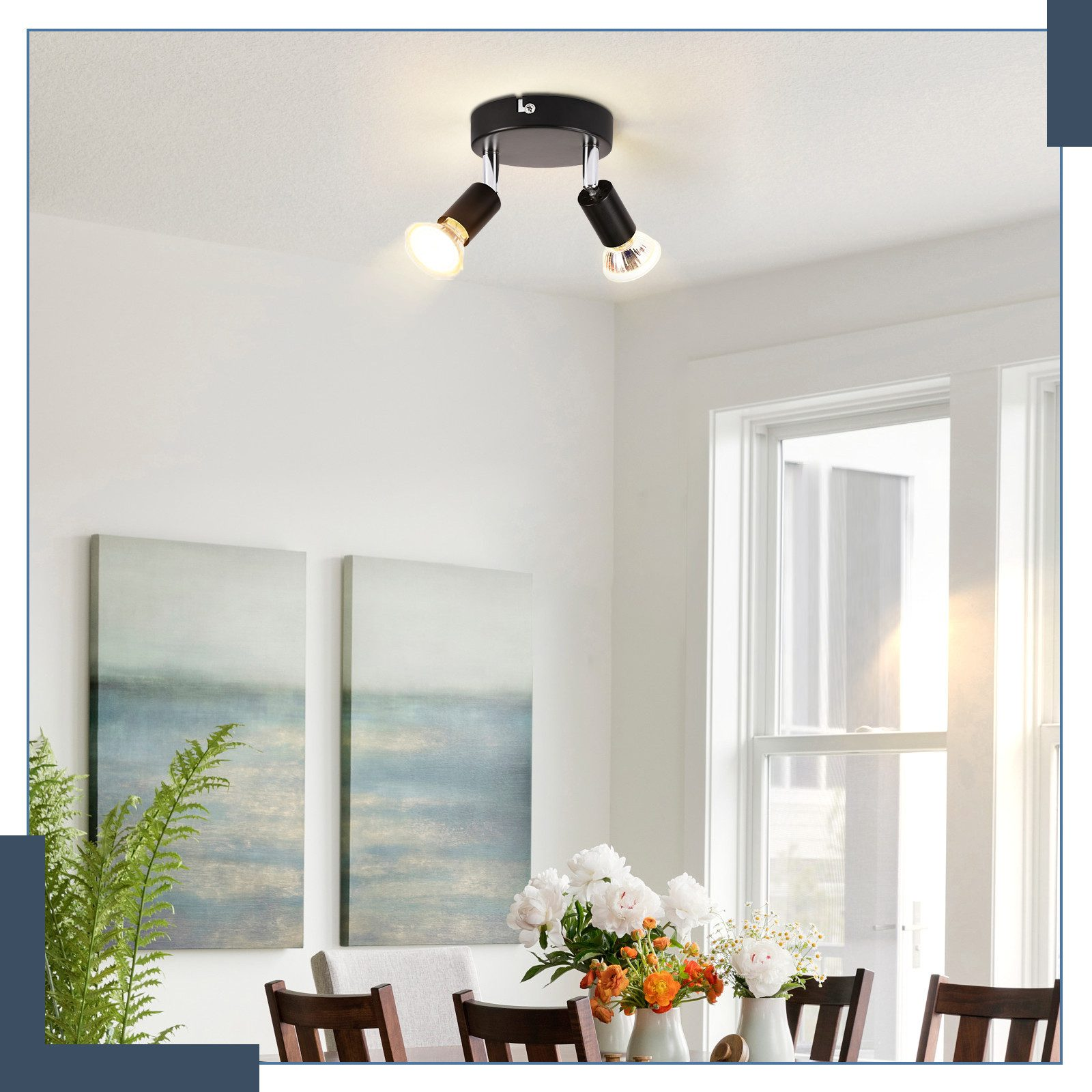 Faretto a due lampadine su un soffitto bianco in una sala da pranzo. Muri bianchi, arte e composizione floreale.
