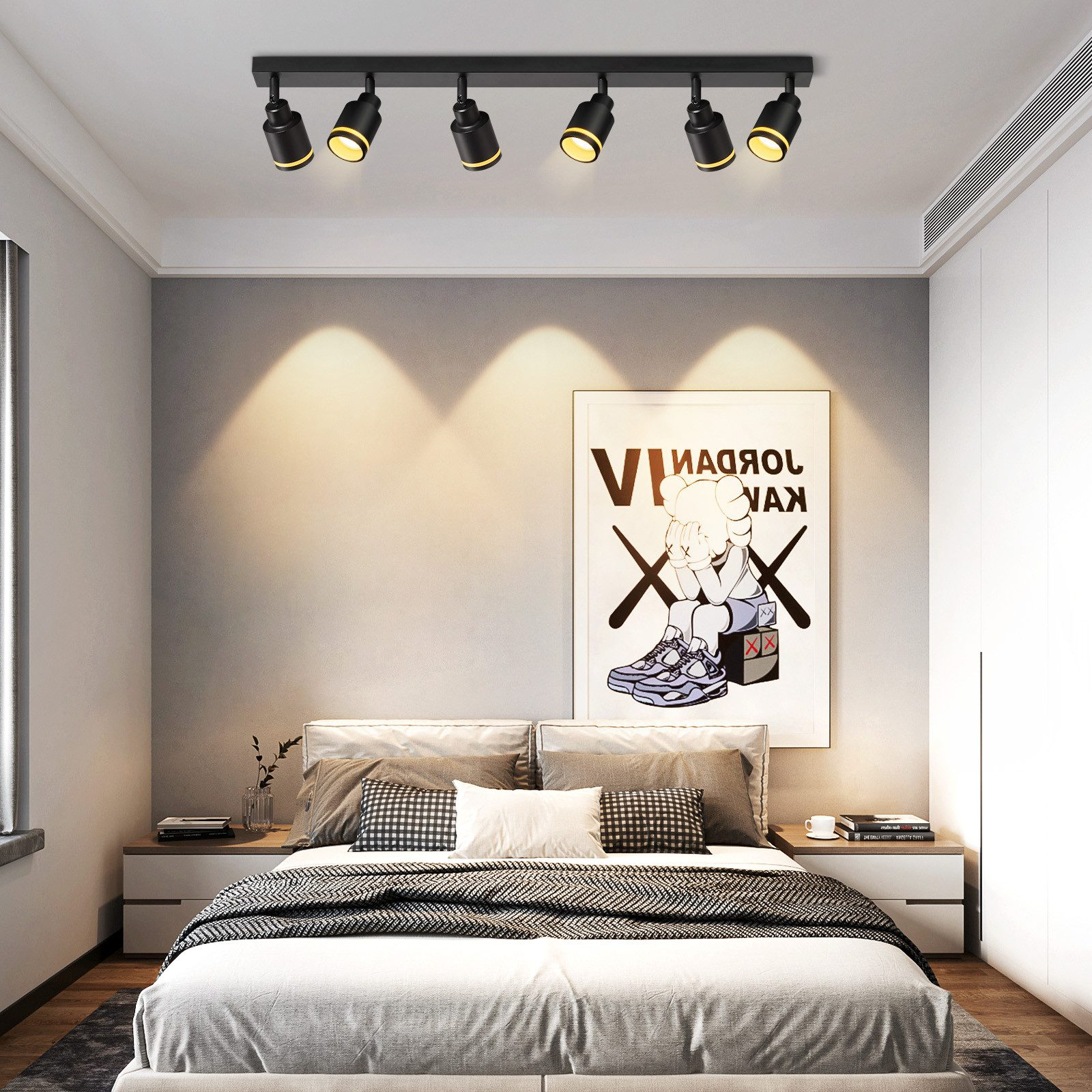 Una camera da letto con un letto, opere d'arte e un binario di faretti a soffitto.