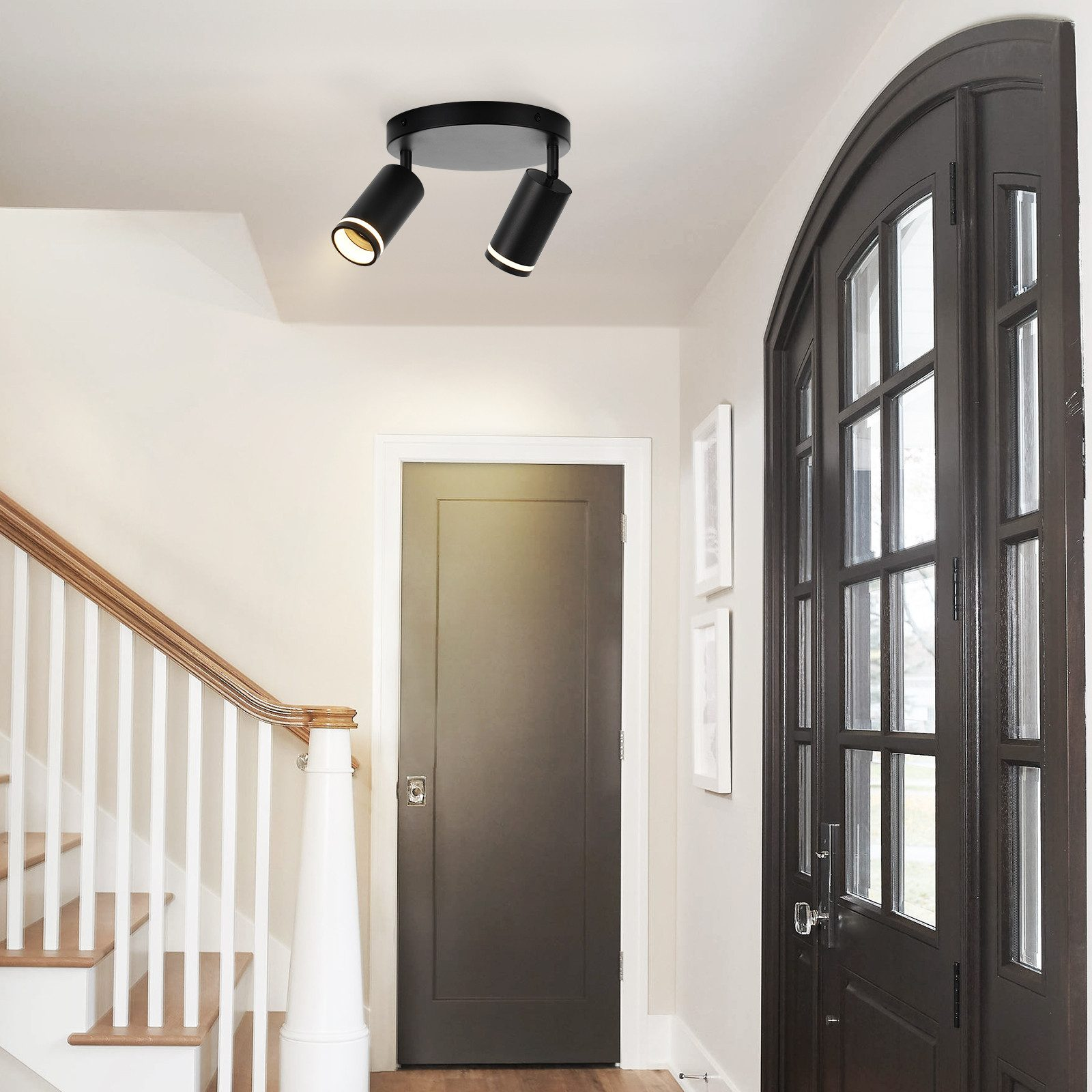 Korytarz ze schodami, drzwiami i dwoma czarnymi reflektorami na suficie.