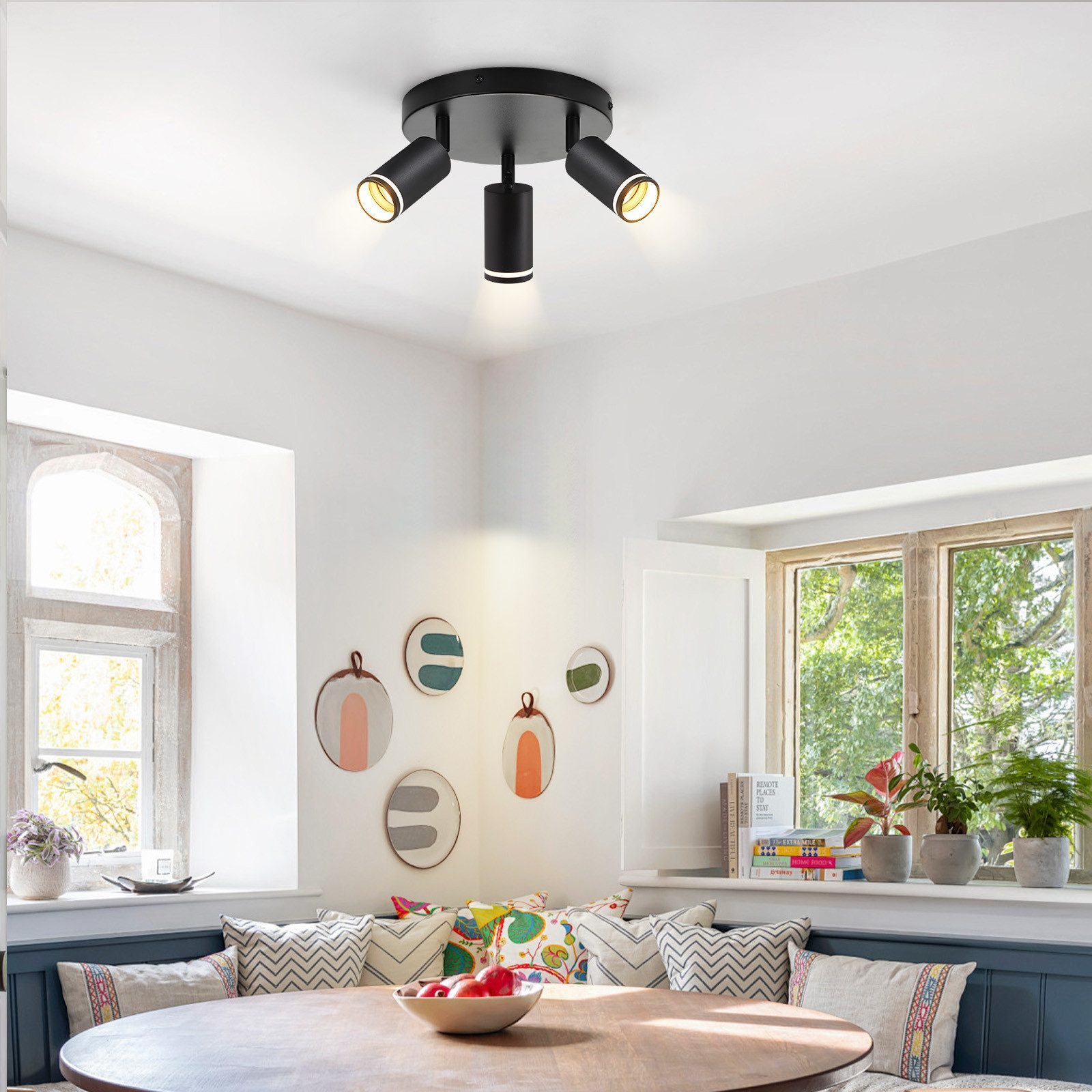 Pokój z białymi ścianami, okrągłym stołem i czarnym oświetleniem punktowym na suficie.