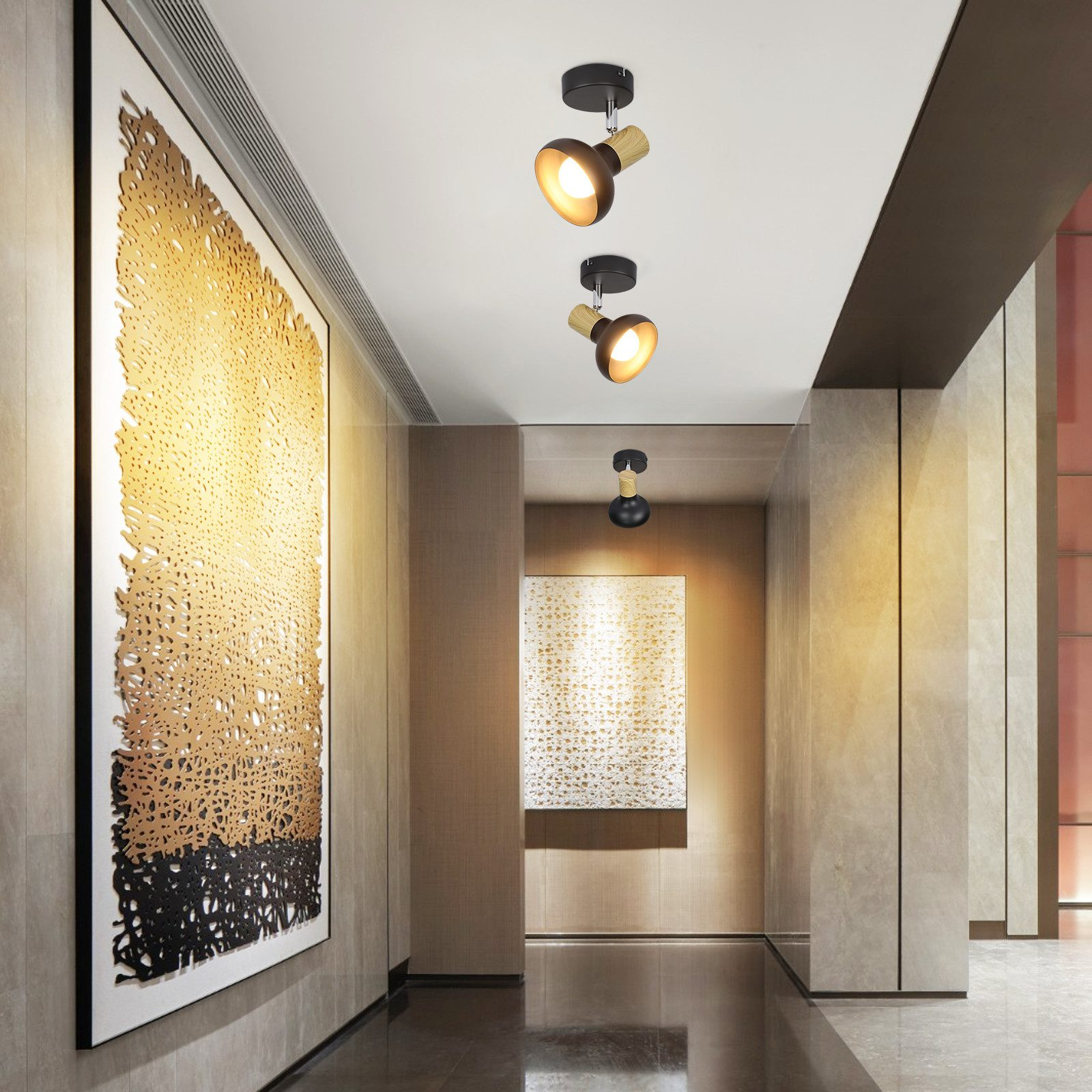 Corridoio con tre faretti sul soffitto, arte alle pareti e pavimento in marmo.