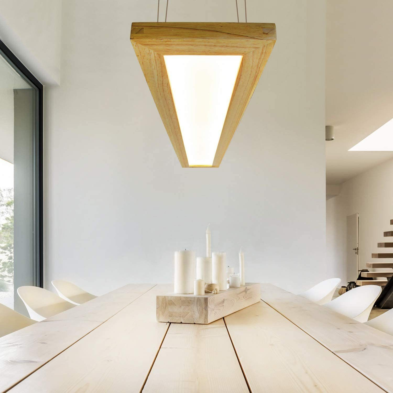 Un apparecchio di illuminazione triangolare in legno sopra un tavolo di legno con candele e sedie bianche.