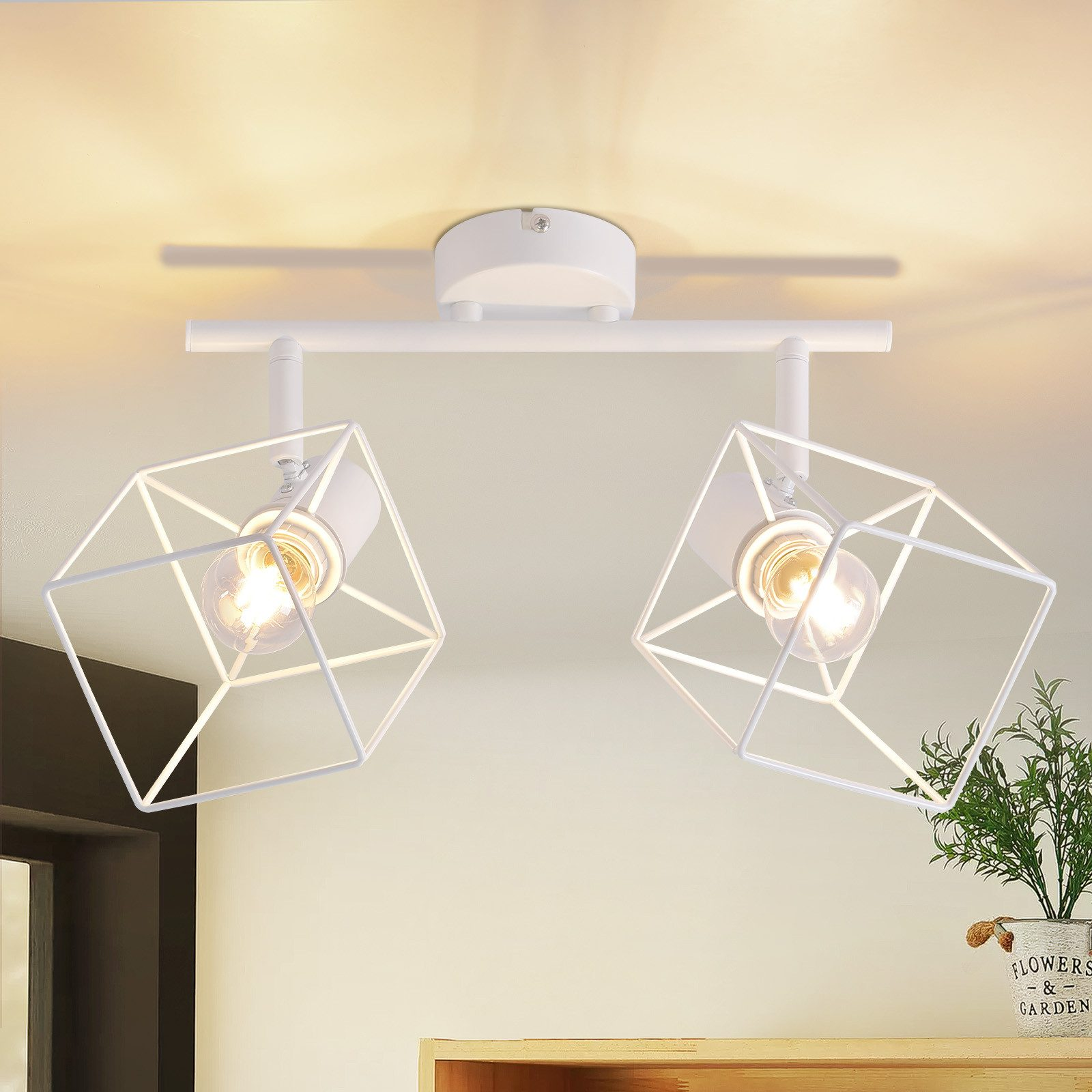 Due faretti da soffitto bianchi e geometrici, ciascuno contenente una lampadina. Le luci sono accese.