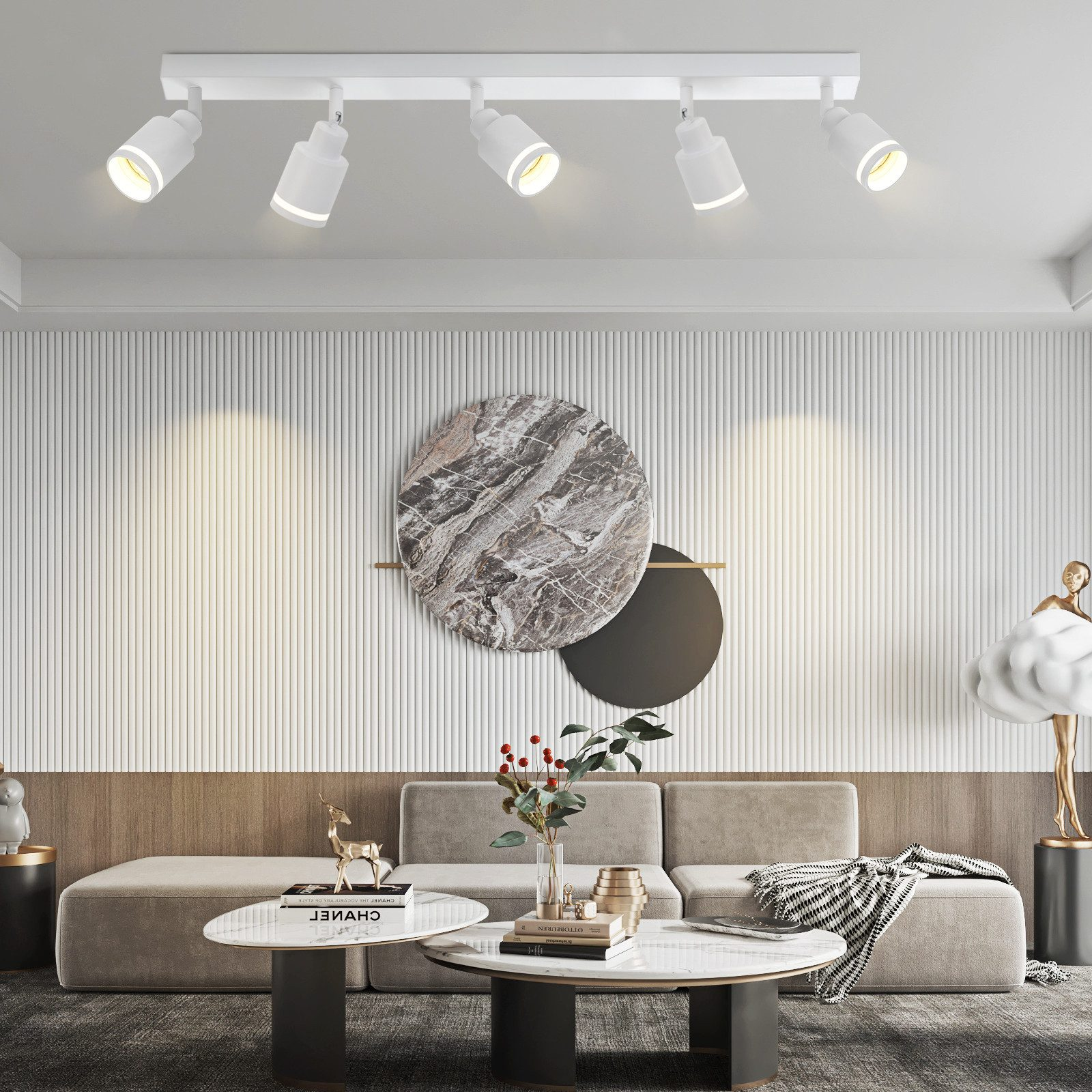 Białe lampy sufitowe z regulowanymi głowicami oświetlają nowoczesny salon o neutralnych tonacjach i wystroju.