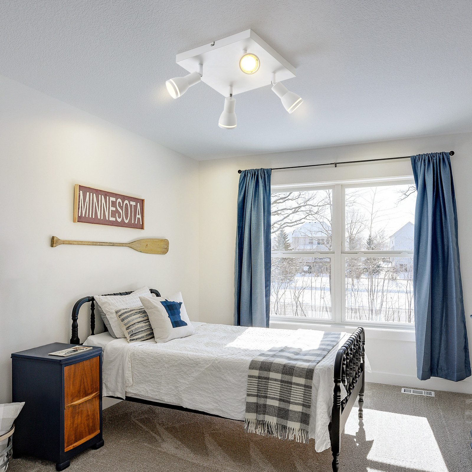 Camera da letto con letto, tende blu e faretti a soffitto. Un cartello dice Minnesota.