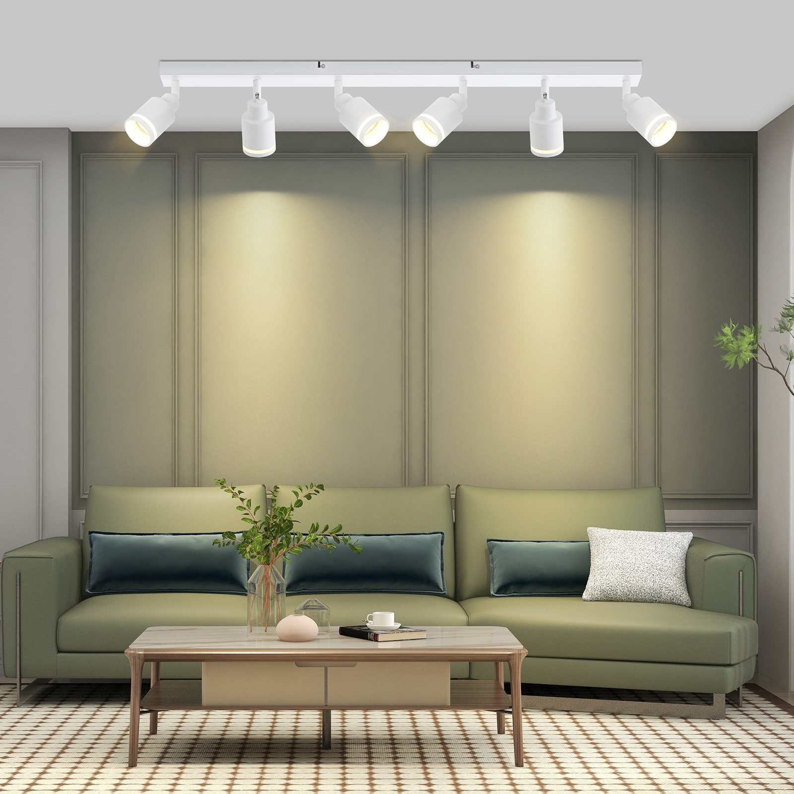 Un sistema di illuminazione a binario con sei faretti bianchi illumina un divano verde e un tavolino.
