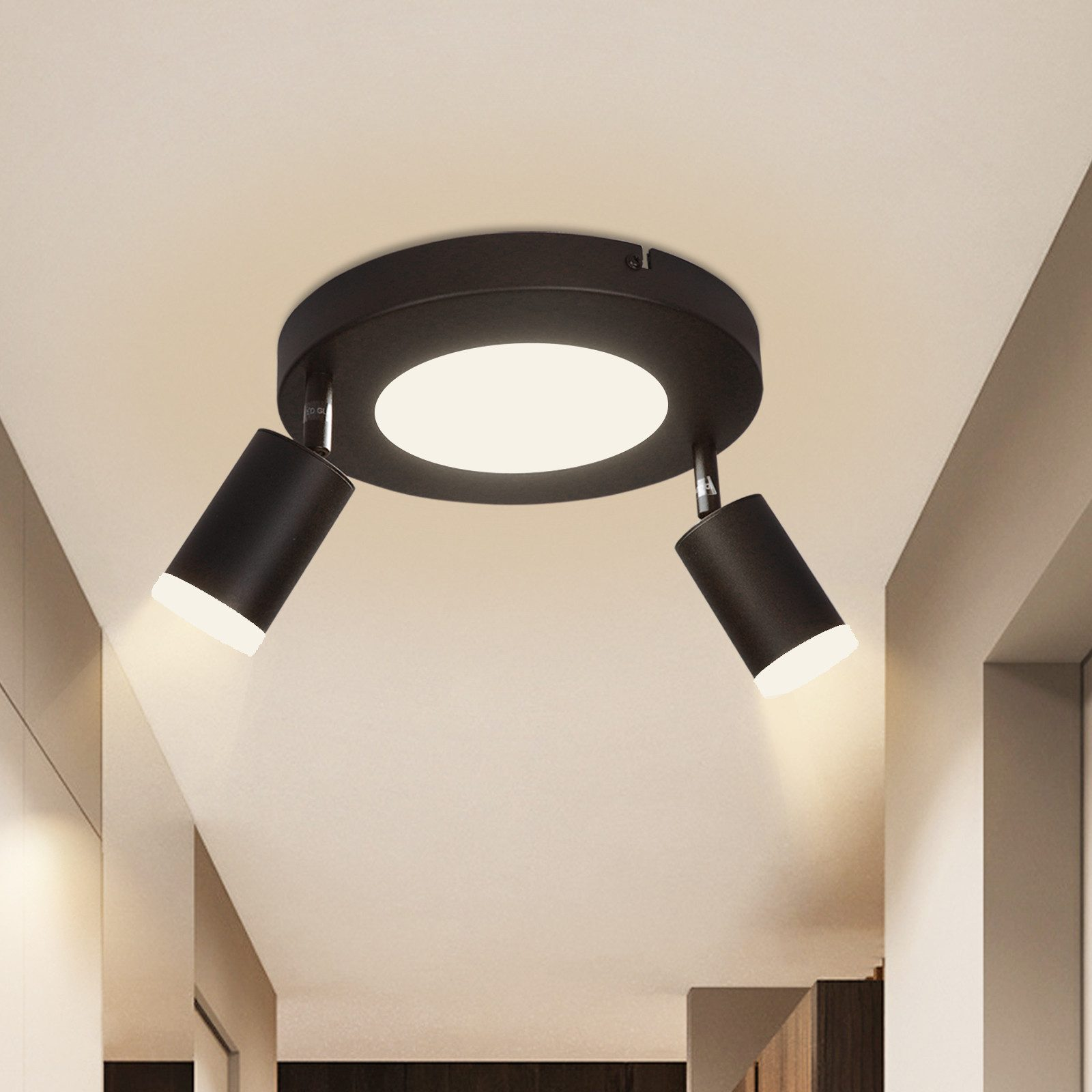 Un faretto da soffitto nero con due luci regolabili e una luce centrale. Le luci sono accese.