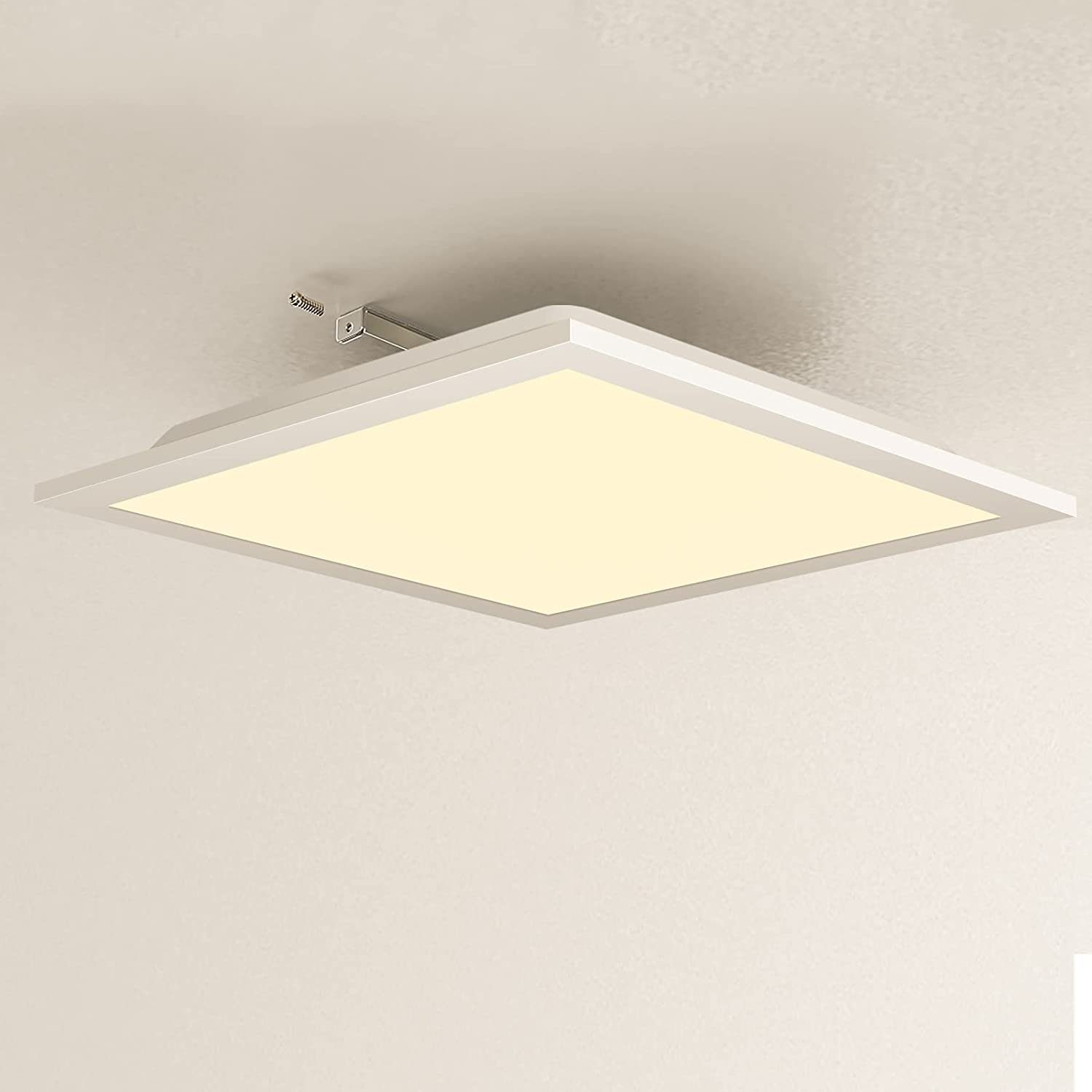 Plafone a soffitto quadrato, bianco, con sorgente luminosa brillante, tonalità gialla. Montato su soffitto bianco.