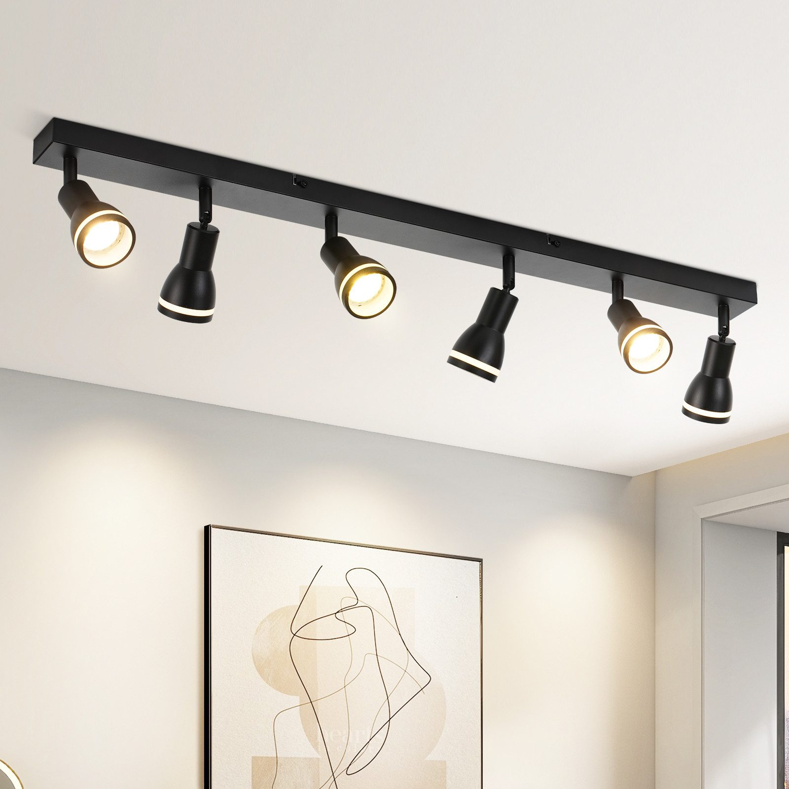 Un soffitto con sei faretti neri montati su una lunga barra nera. Le luci sono rivolte verso il basso.