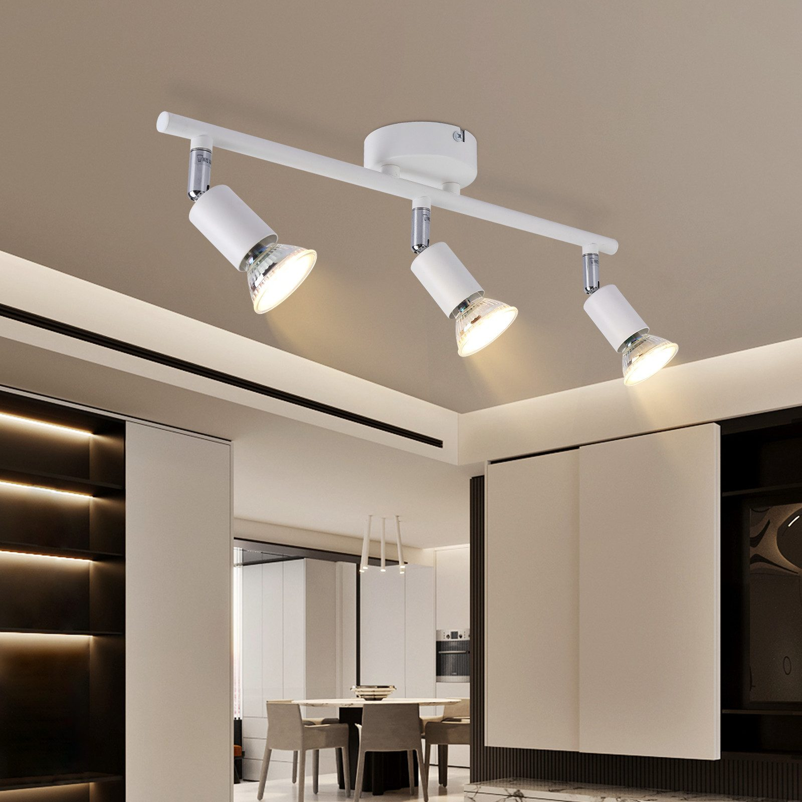 Binario di illuminazione bianco con tre faretti regolabili su una barra bianca, montati su un soffitto bianco.