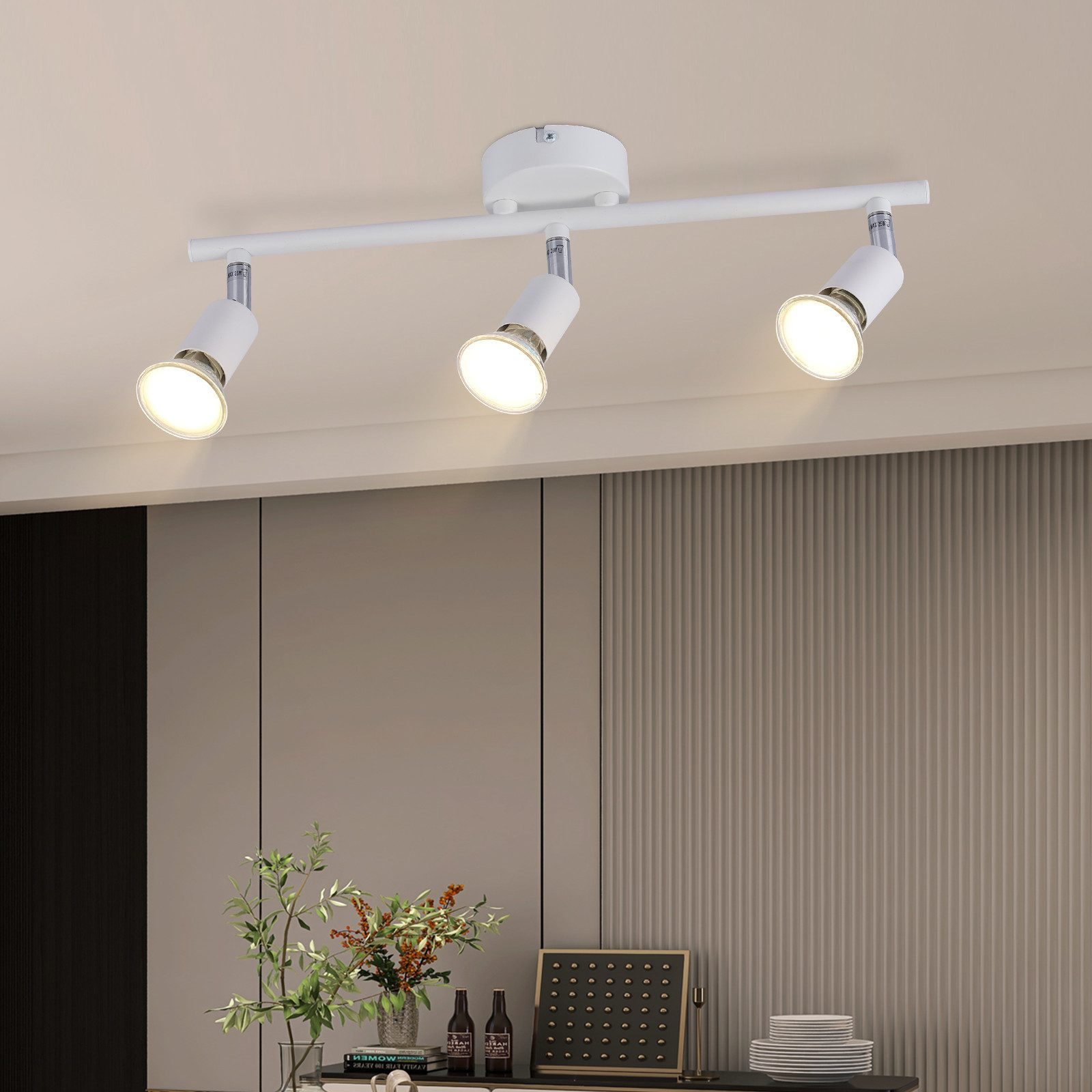 Una lampada da soffitto bianca con tre faretti orientabili, montati su una barra bianca.