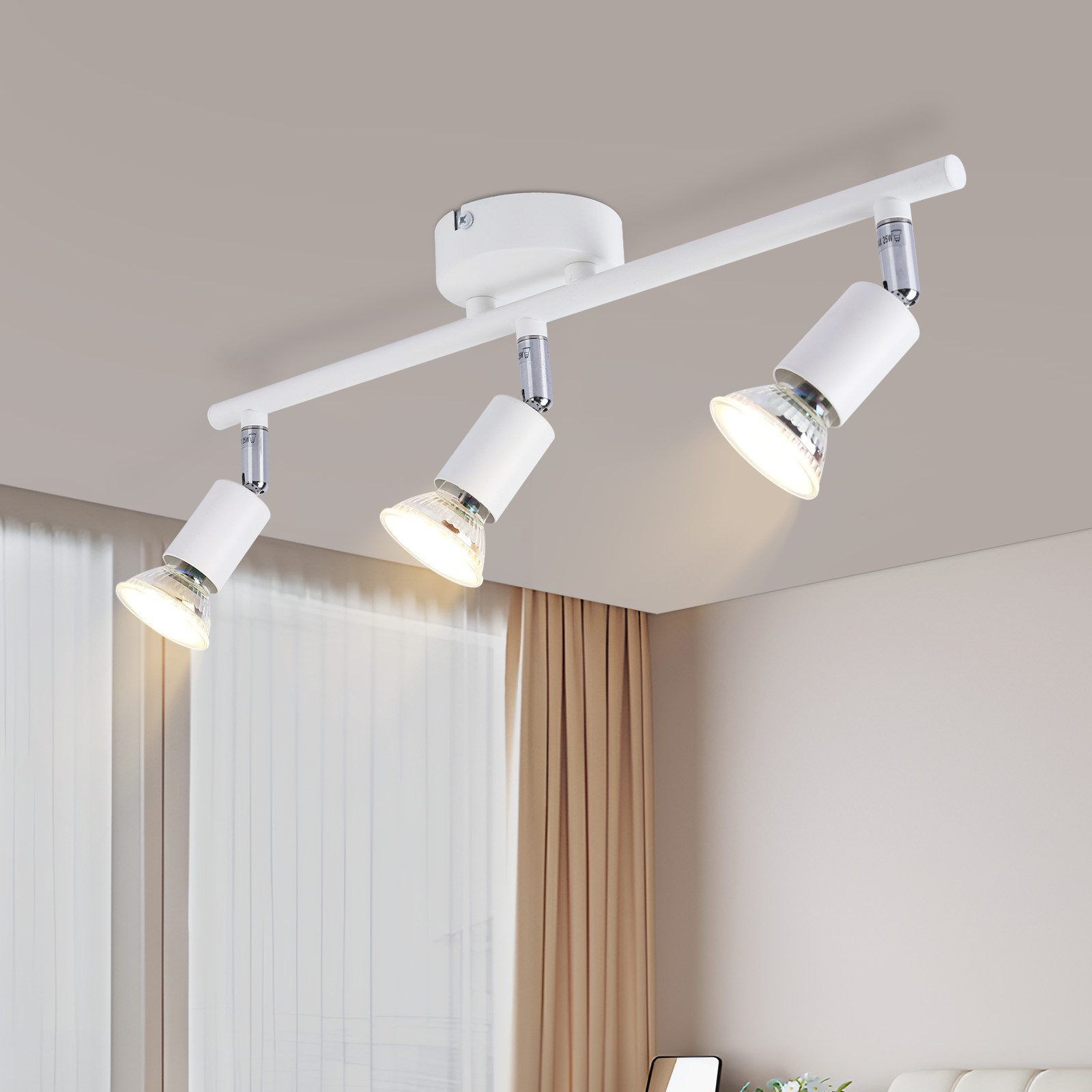 Una plafoniera bianca con tre faretti orientabili, montata su un soffitto bianco, illuminata.