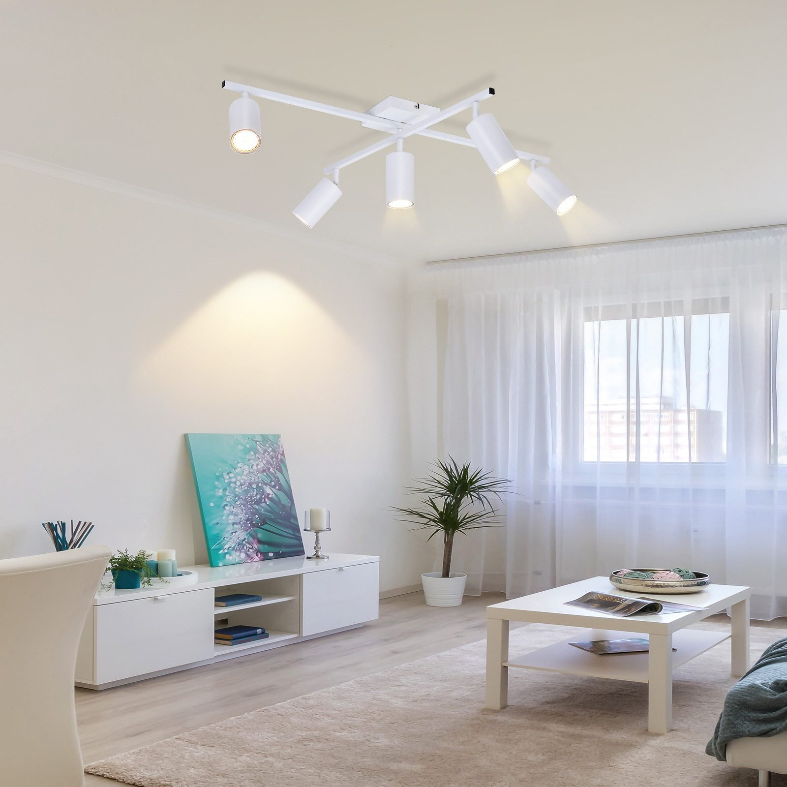 Un soggiorno con pareti bianche, una luce a soffitto bianca, mobili bianchi e una finestra.