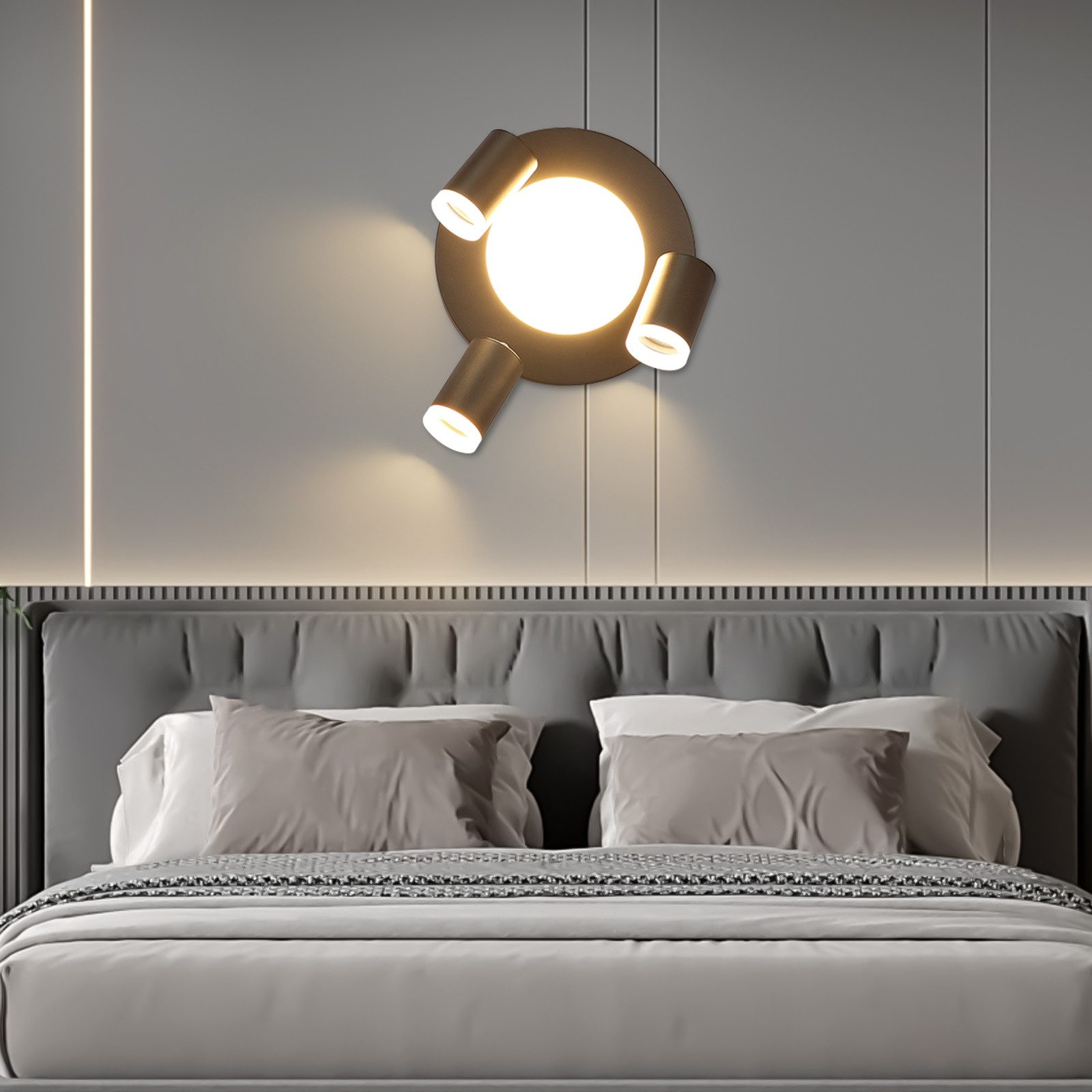 Un'applique con tre faretti sopra un letto. Il muro è grigio.
