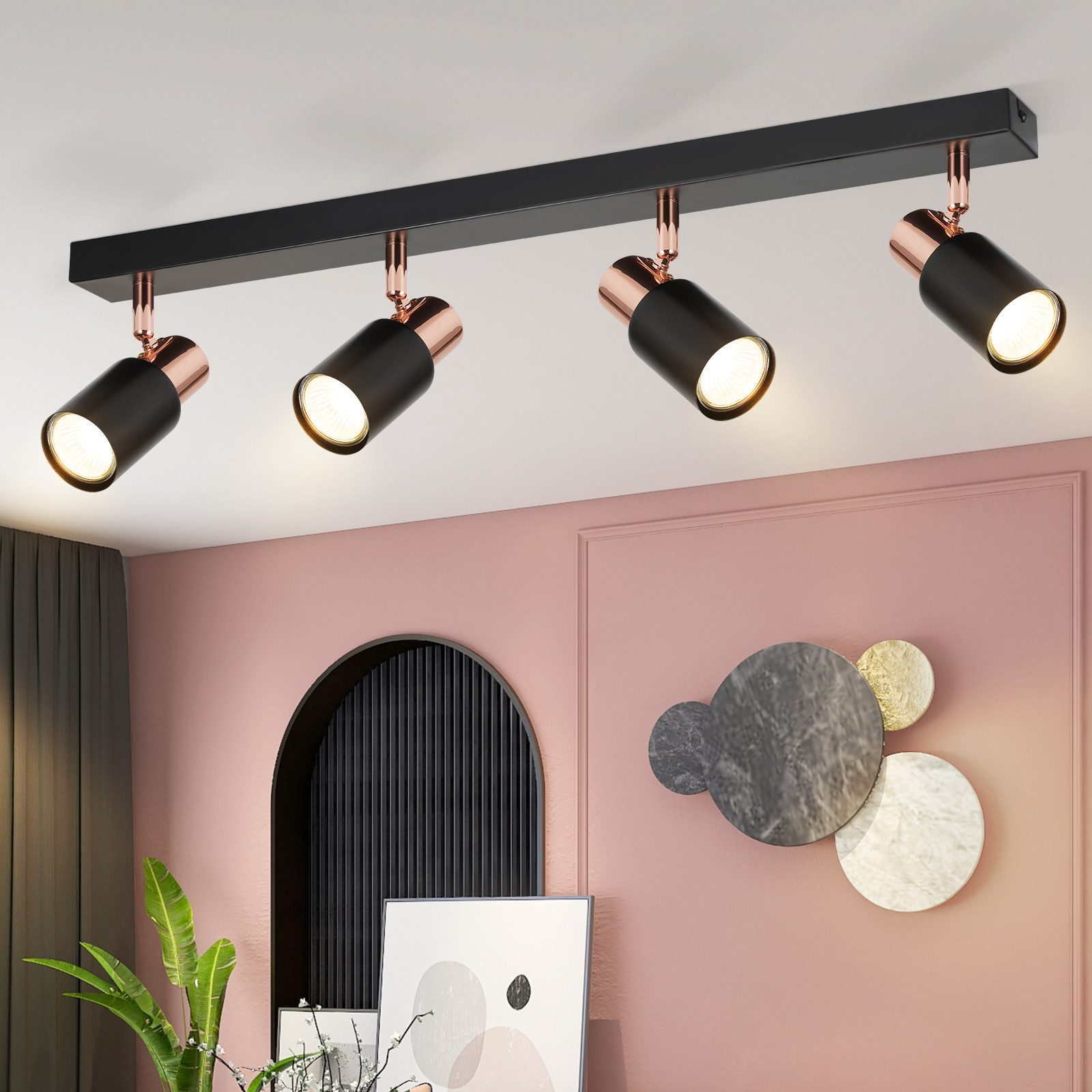 Faretti a soffitto, neri con dettagli oro rosa, illuminano una stanza rosa con decorazioni.