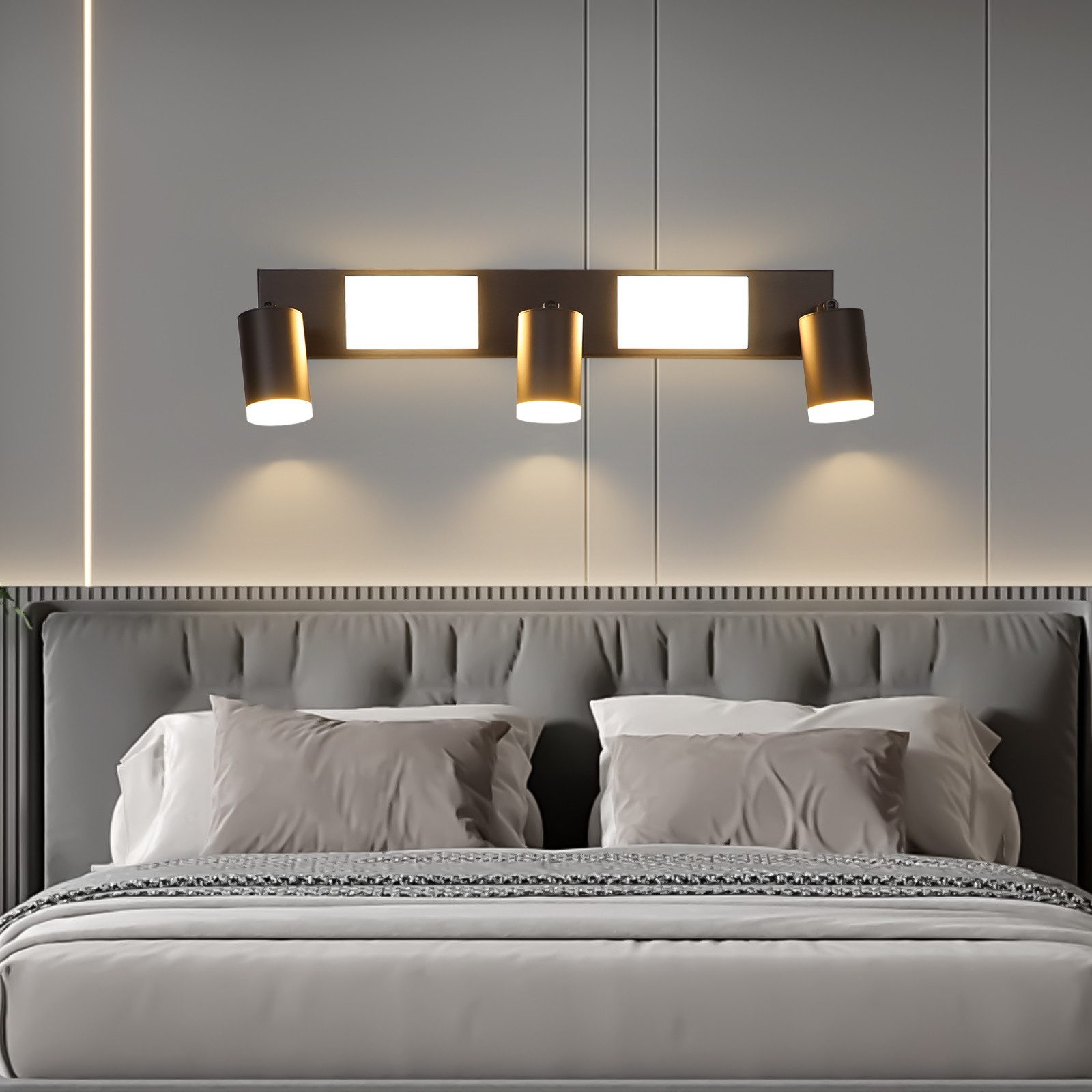 Una lampada da parete con tre faretti sopra un letto.