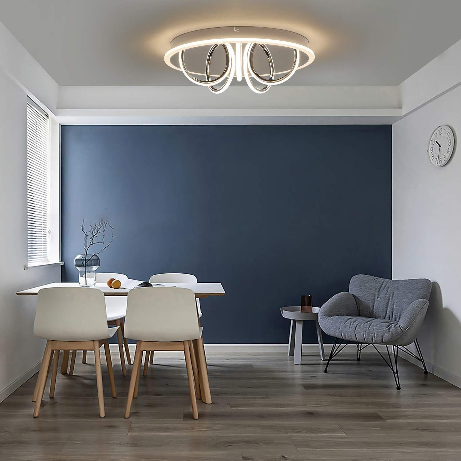Una sala da pranzo moderna con tavolo bianco, sedie e parete blu. Un lampadario circolare.