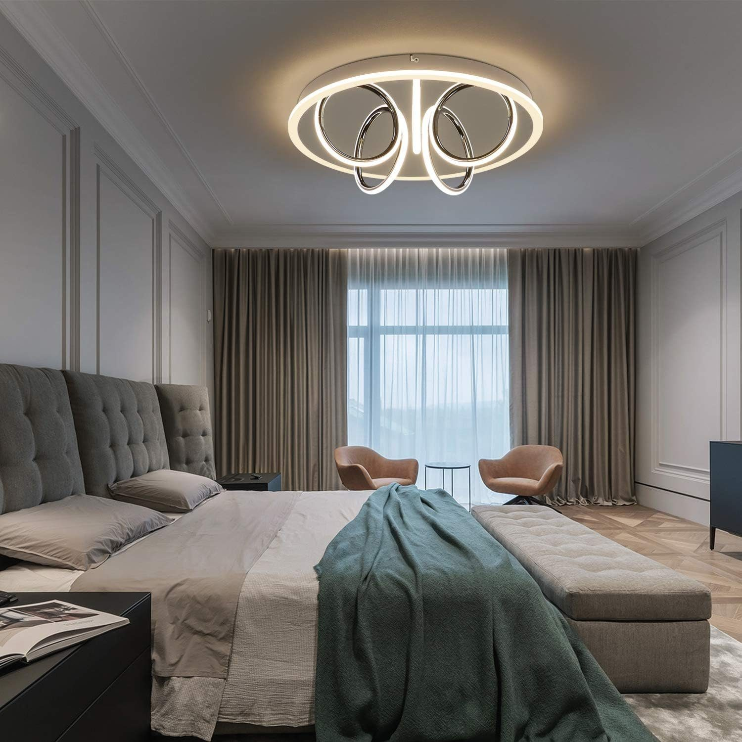 Una camera da letto moderna con una luce a soffitto, un letto e tende. Sono visibili anche due poltrone.