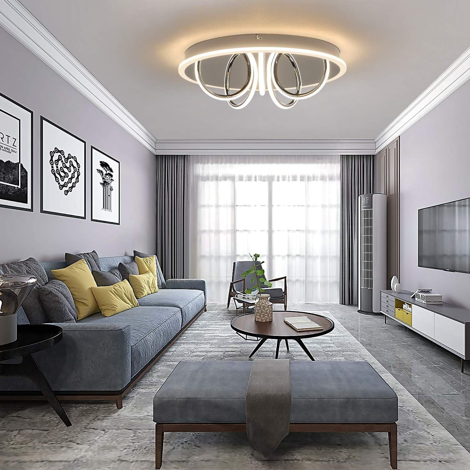 Ein modernes Wohnzimmer mit einem grauen Sofa, Fernseher und einer einzigartigen Deckenleuchte mit rundem Design.