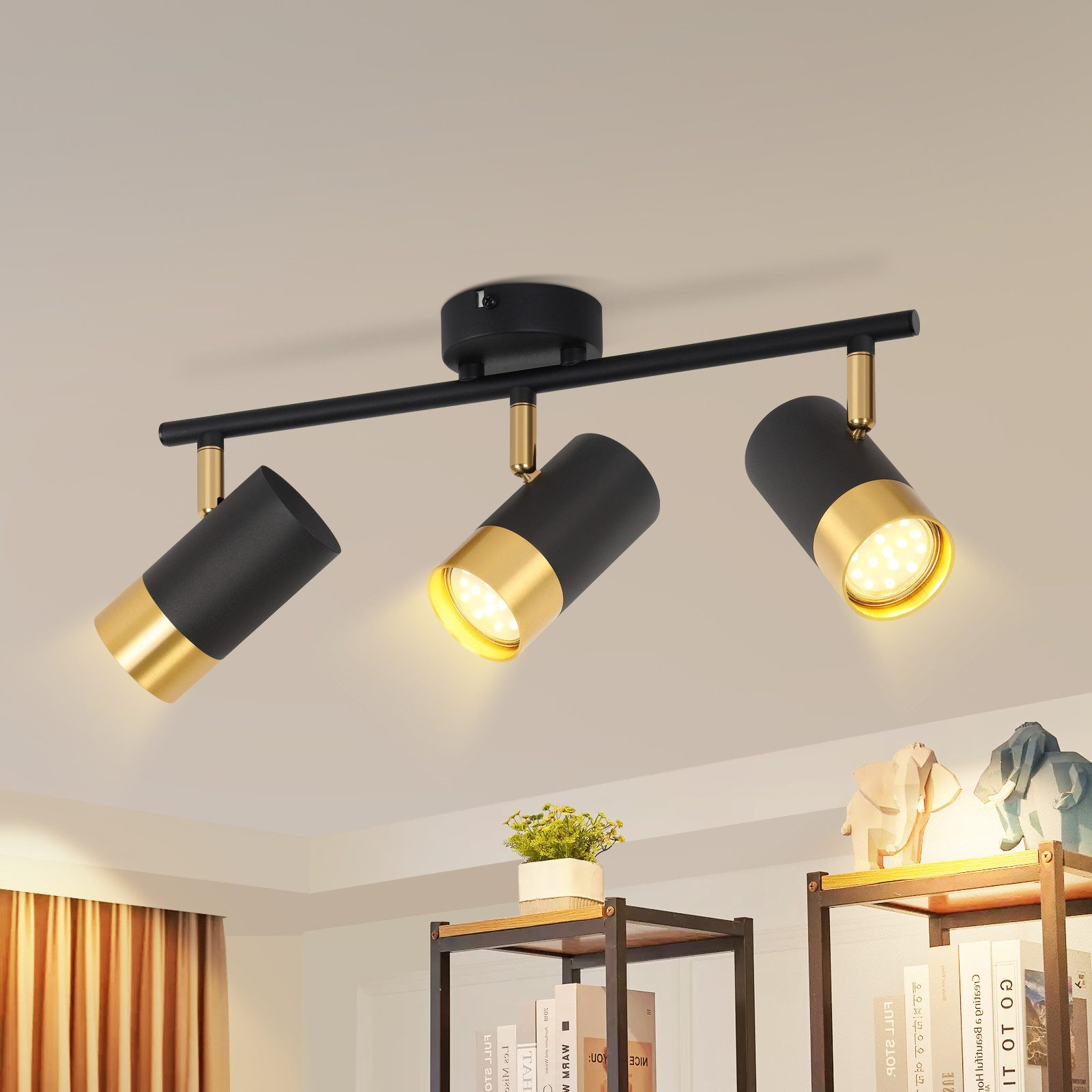 Lampada da soffitto con tre faretti neri e oro. La luce brilla verso il basso.
