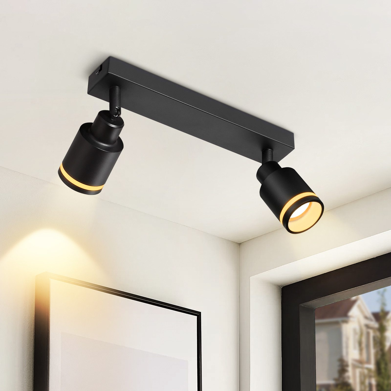 Un apparecchio di illuminazione nero su un soffitto bianco con due faretti. La luce è accesa.