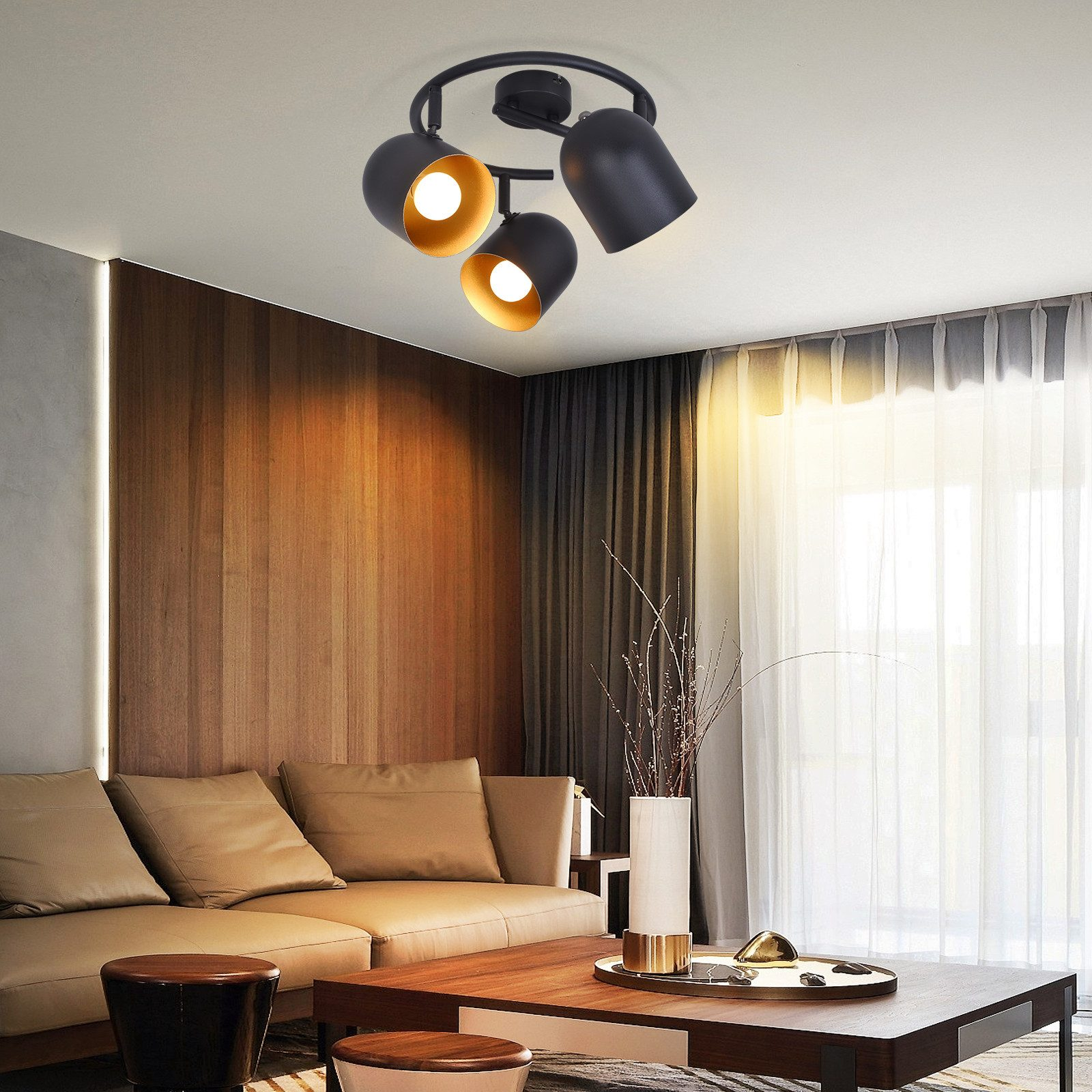 Un lampadario con tre luci sferiche nere. La stanza ha una parete in legno e un divano.