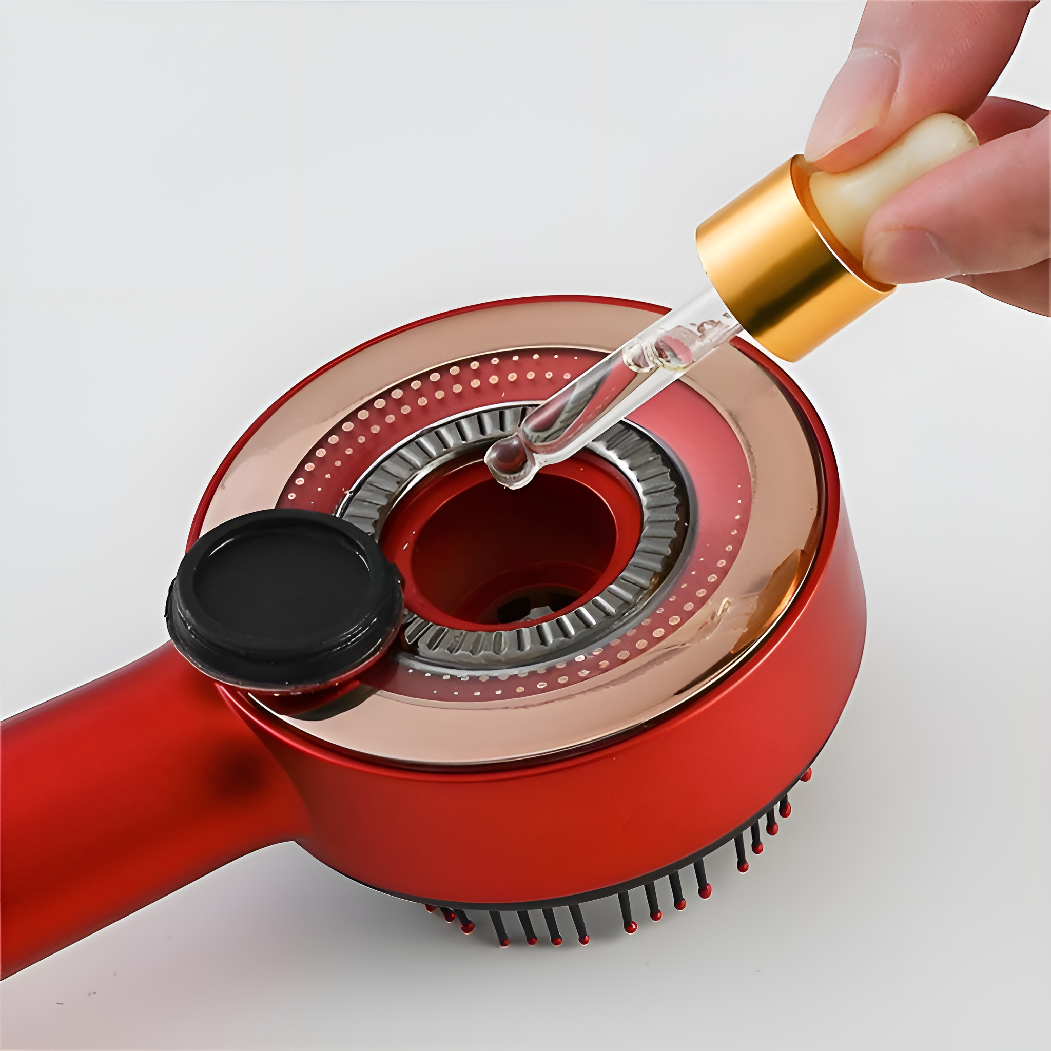 Eine Hand, die Flüssigkeit aus einer Pipette in eine rote Haarbürste gießt.
