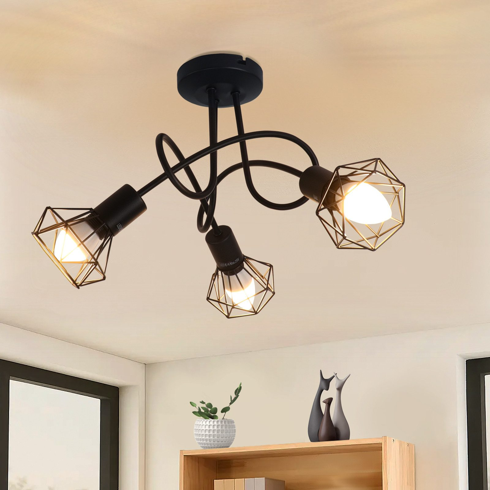 Tre lampade con struttura in metallo nero, con oro all'interno, appese al soffitto.