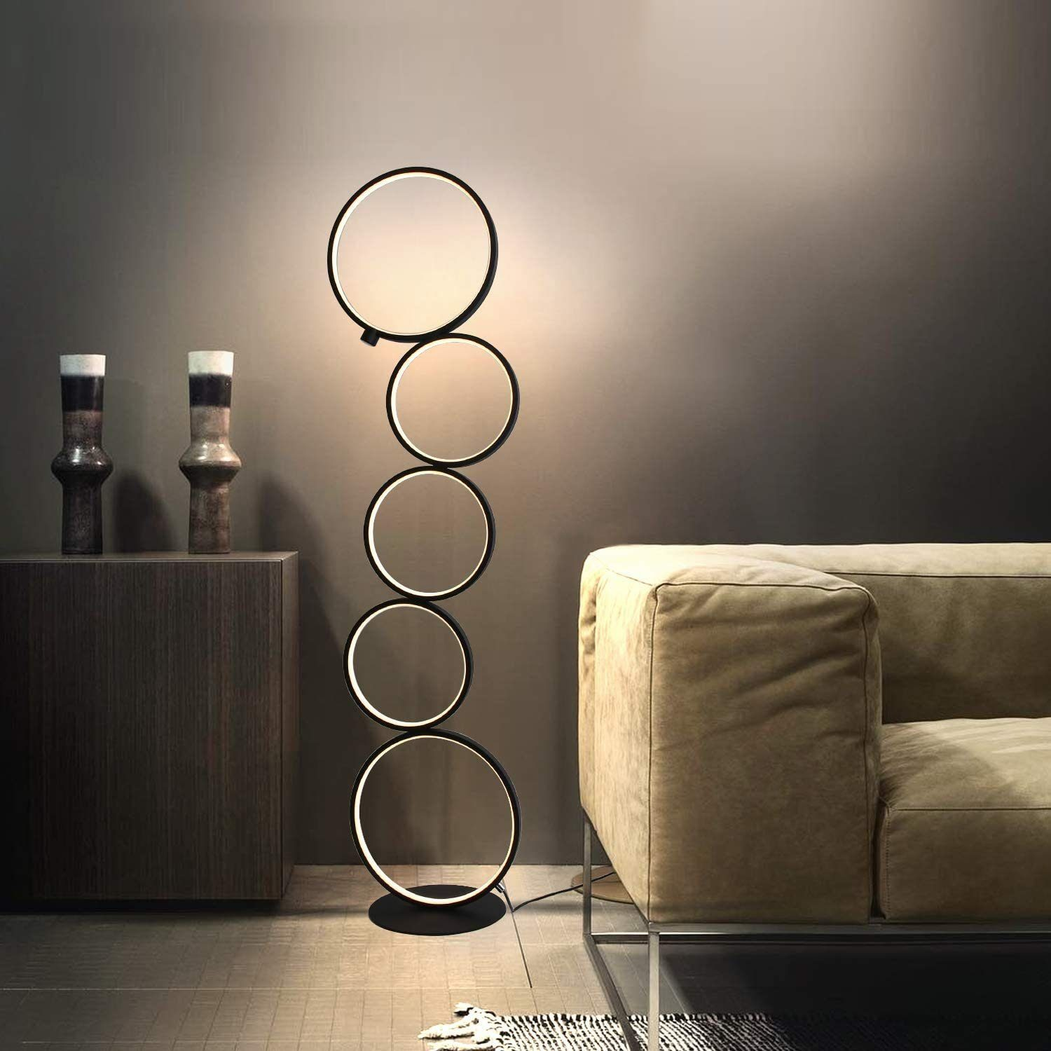 Schwarze Stehlampe mit fünf kreisförmigen Lichtern in einem minimalistischen Wohnzimmer.