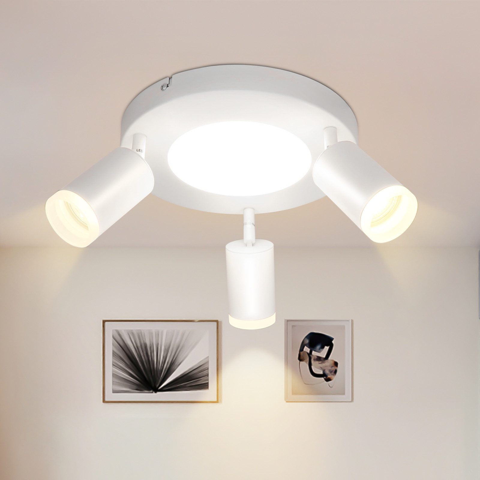 Un faretto da soffitto bianco con tre luci regolabili. Ci sono dipinti sullo sfondo.