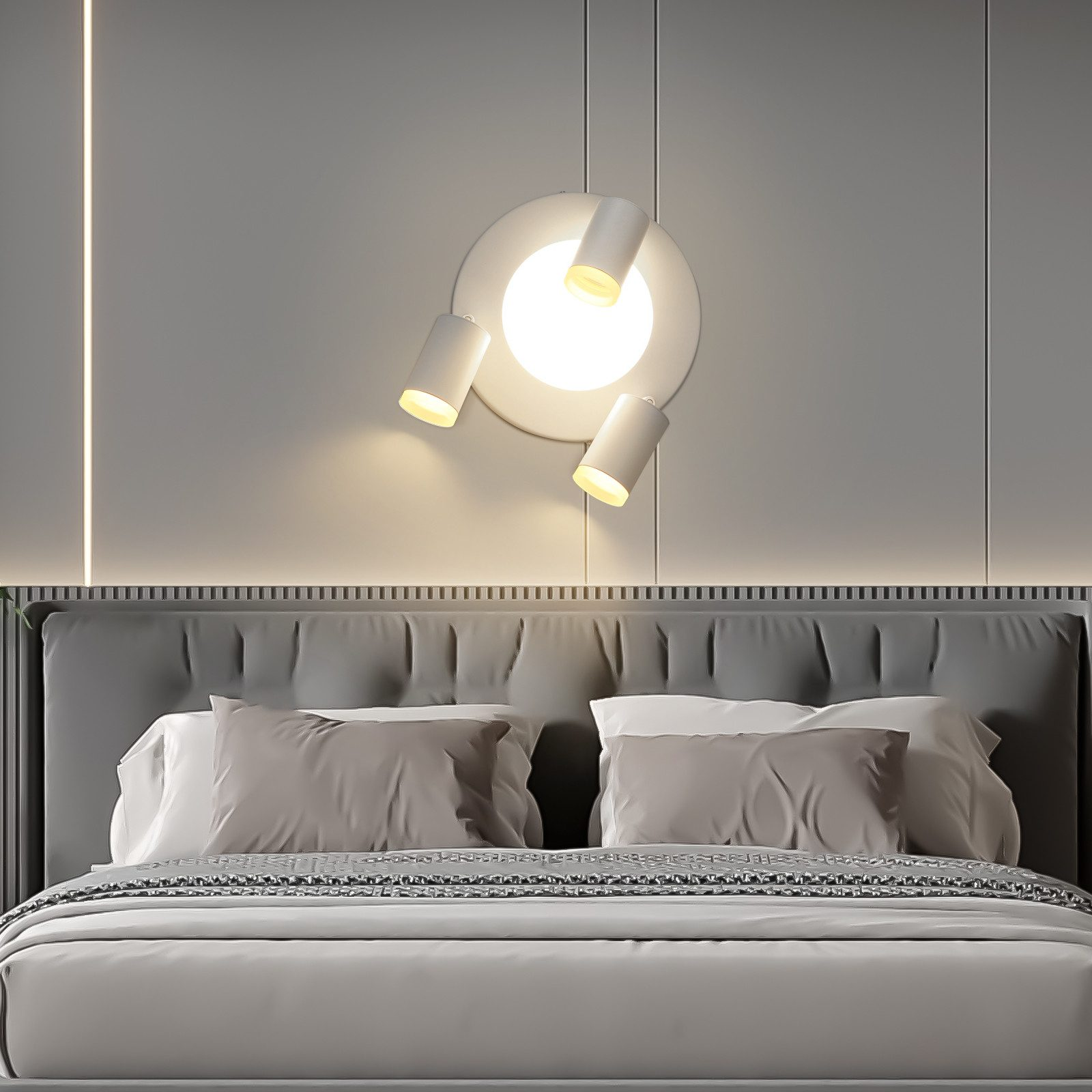 Letto con testiera grigia, illuminato da un lampadario a soffitto con tre faretti.