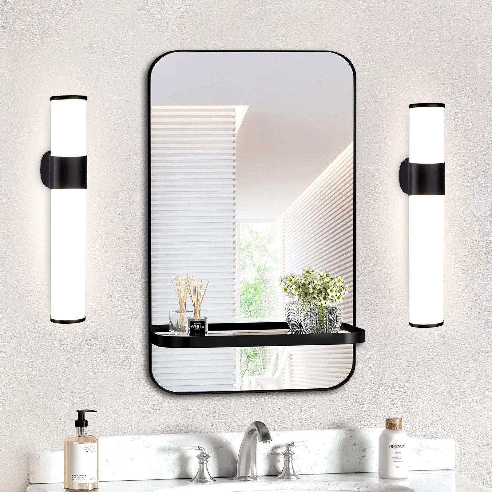 Bagno con specchio, luci e un ripiano con oggetti su una parete bianca.