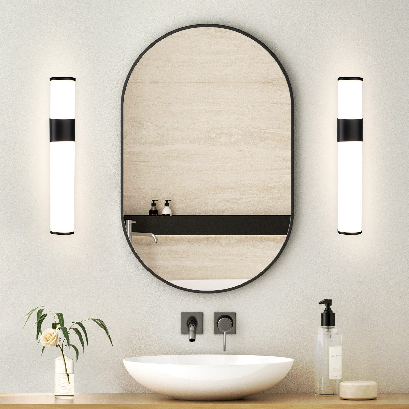 Badezimmer mit ovalem Spiegel, zwei Wandleuchten, einem Waschbecken und dekorativen Elementen. Sauber und modern.