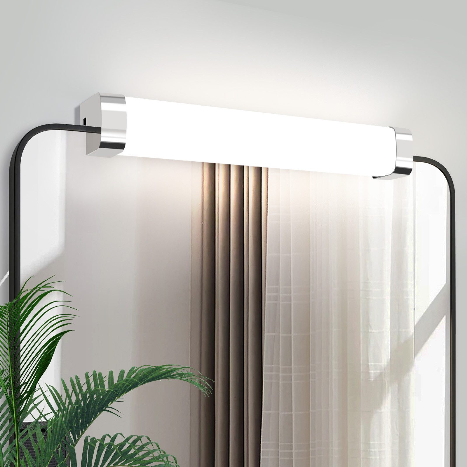 Uno specchio con un'apparecchio di illuminazione integrato sopra, con una pianta verde sul lato sinistro.