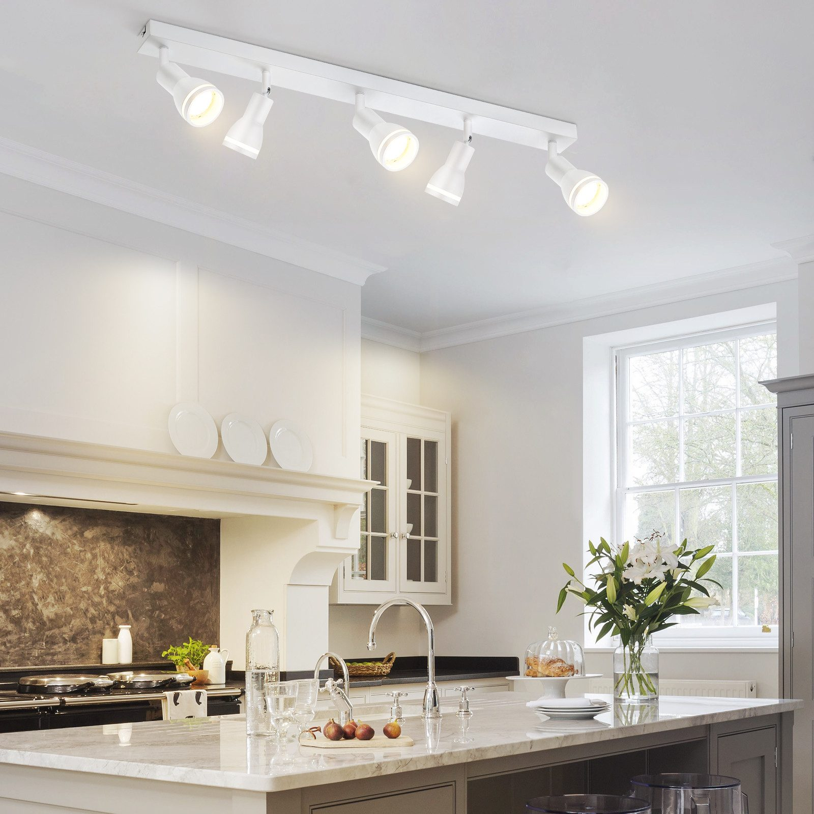 Una cucina con una lampada da soffitto bianca con faretti sopra un'isola cucina, che mostra l'interior design.