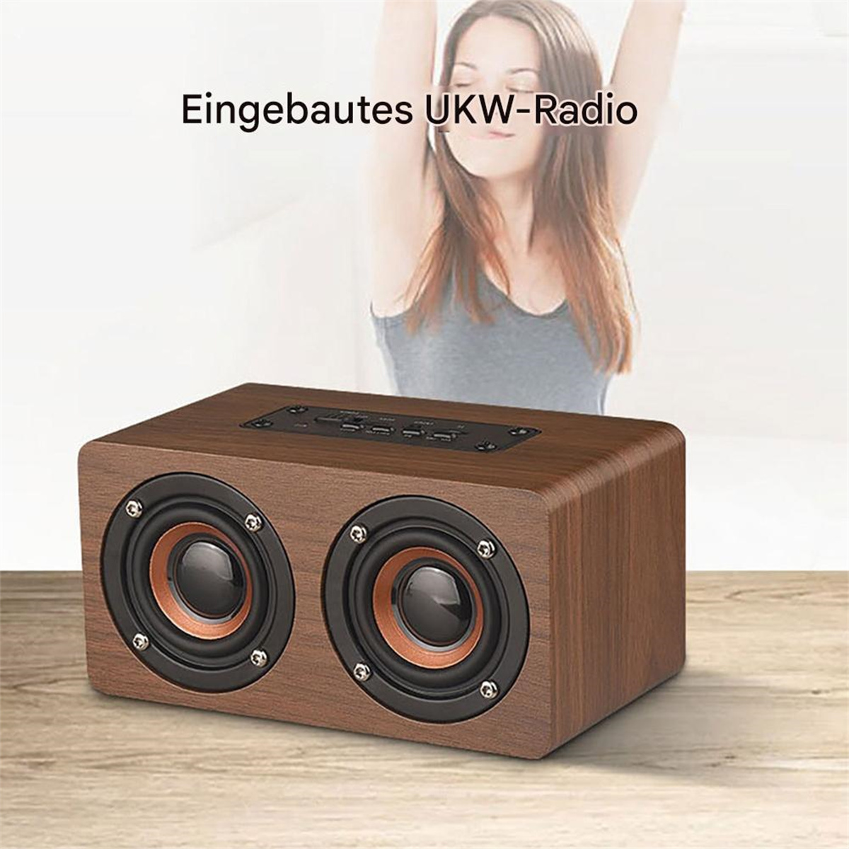 Holzlautsprecher auf einem Holztisch. Im Hintergrund eine Frau. Der Lautsprecher hat zwei Lautsprechereinheiten.