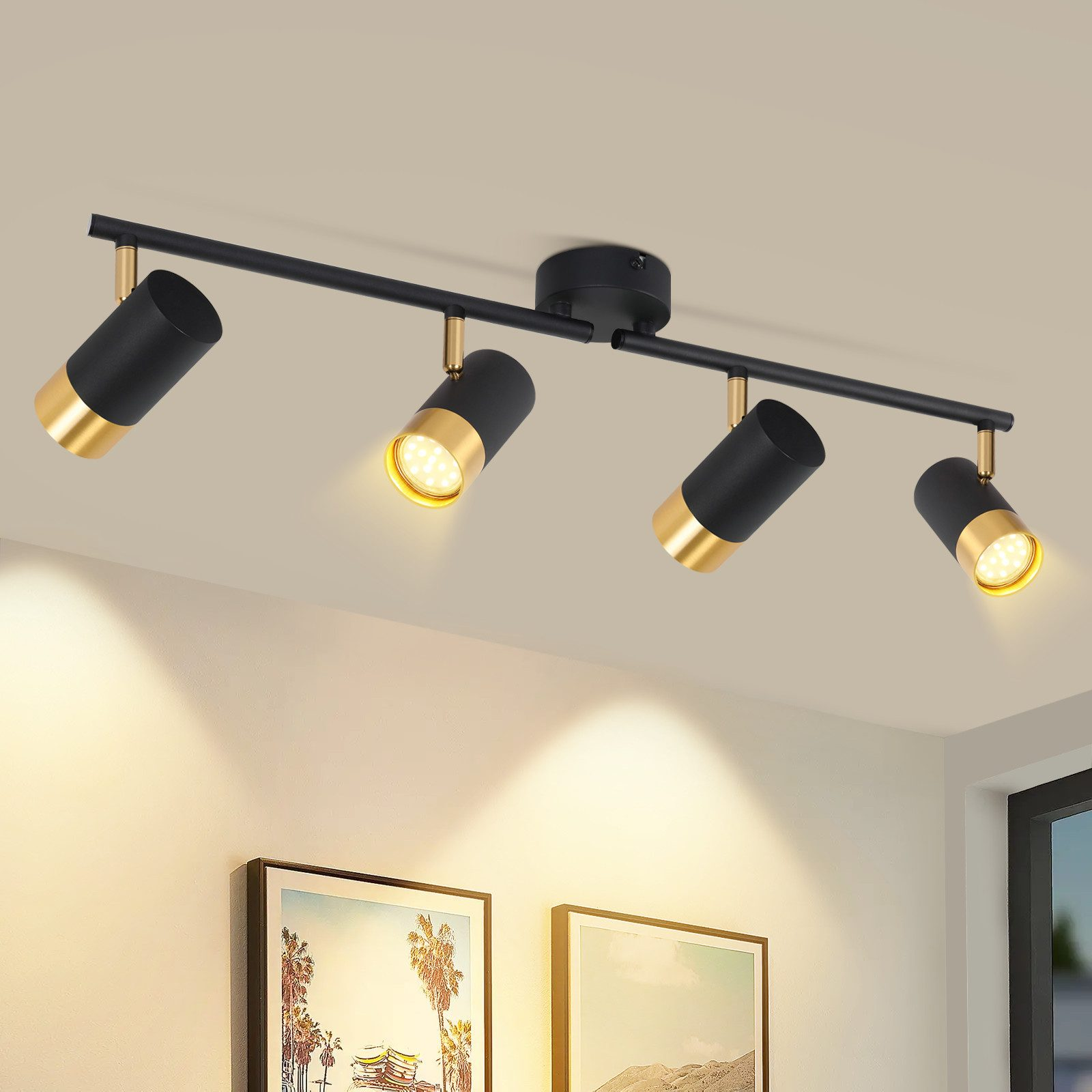 Quattro faretti neri e oro fissati su una barra nera, montati su un soffitto bianco.