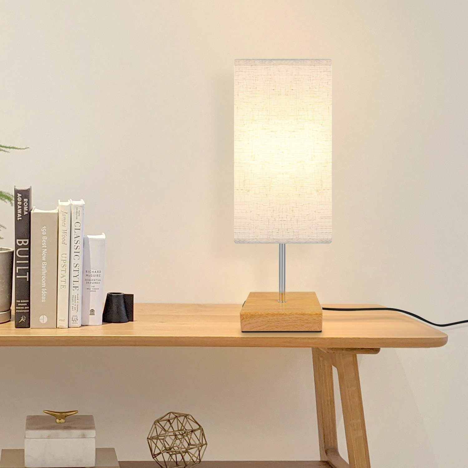 Lampa z drewnianą podstawą i prostokątnym, materiałowym abażurem umieszczona na drewnianym stole.