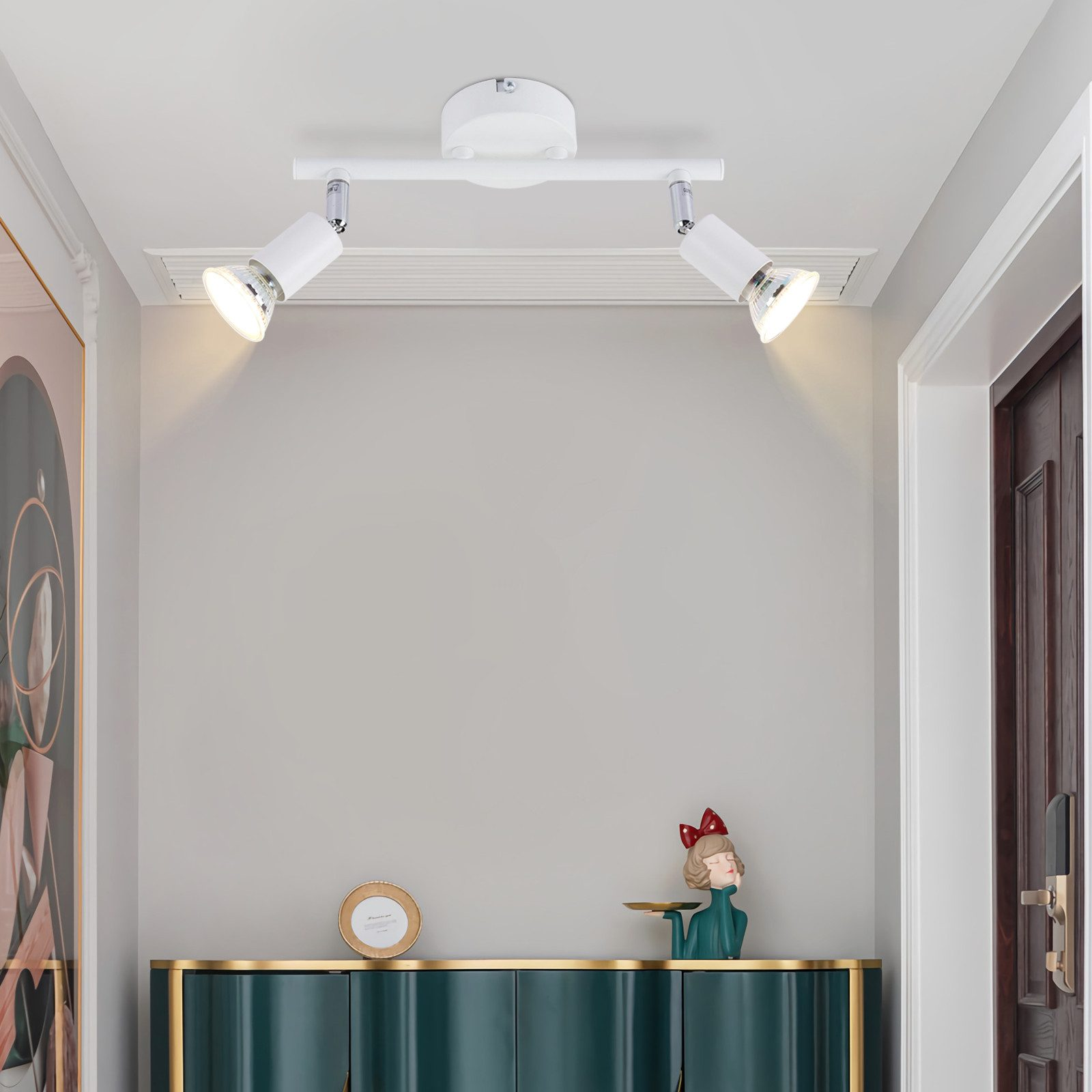 Un corridoio con una lampada da soffitto bianca con faretti, montata sul soffitto, che illumina lo spazio.