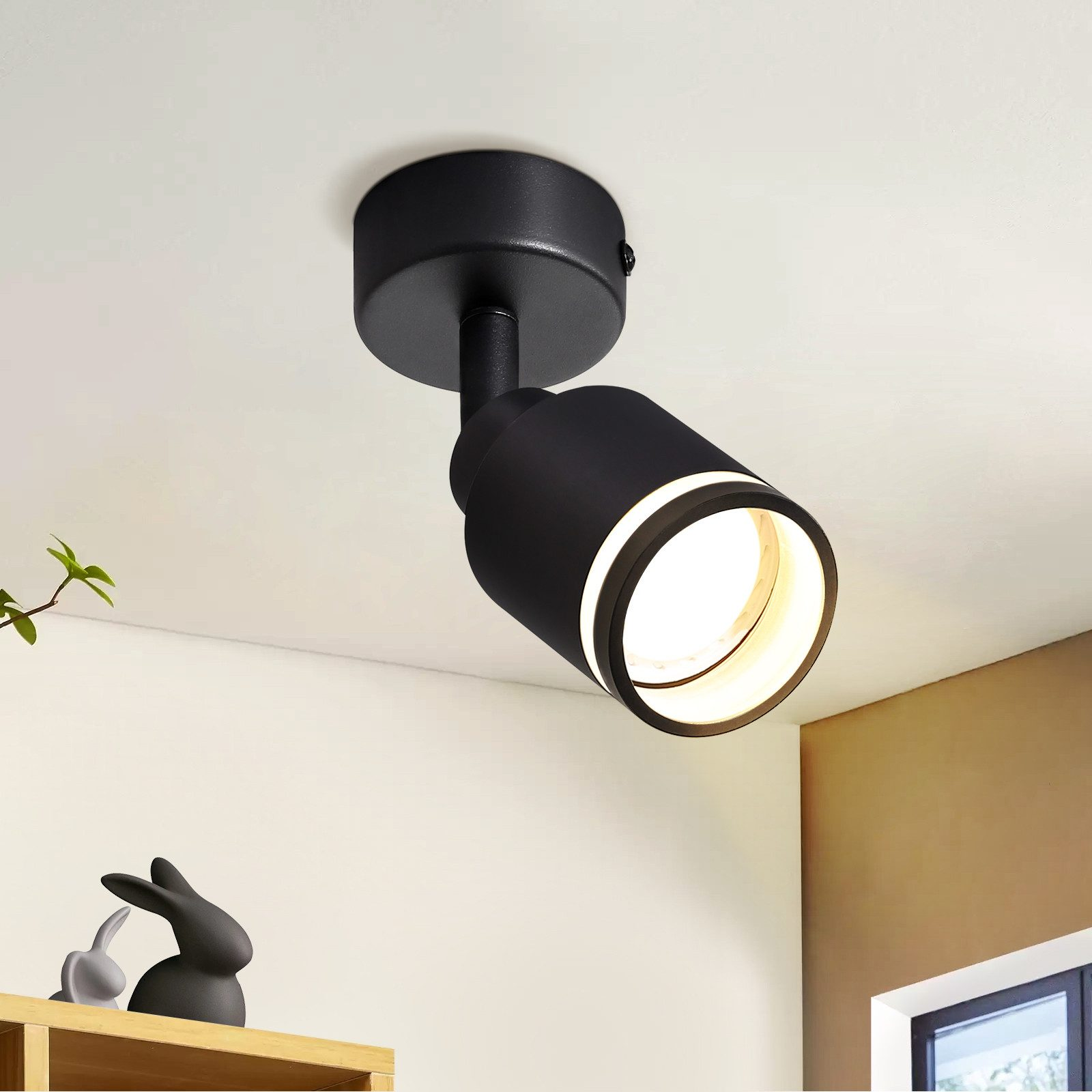 Faretto da soffitto nero inclinato verso il basso. Ha un design circolare ed è montato su un soffitto bianco.