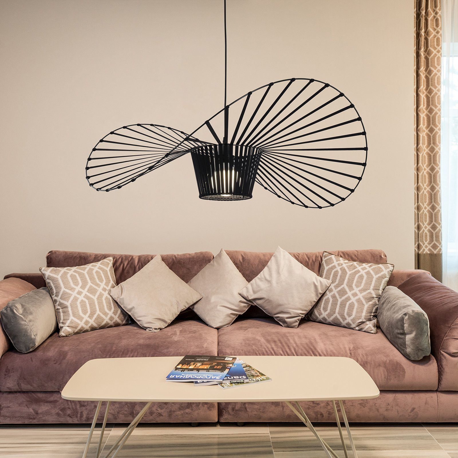 Modernes Wohnzimmer mit rosa Sofa, Kissen, Couchtisch und großer schwarzer Deckenleuchte.